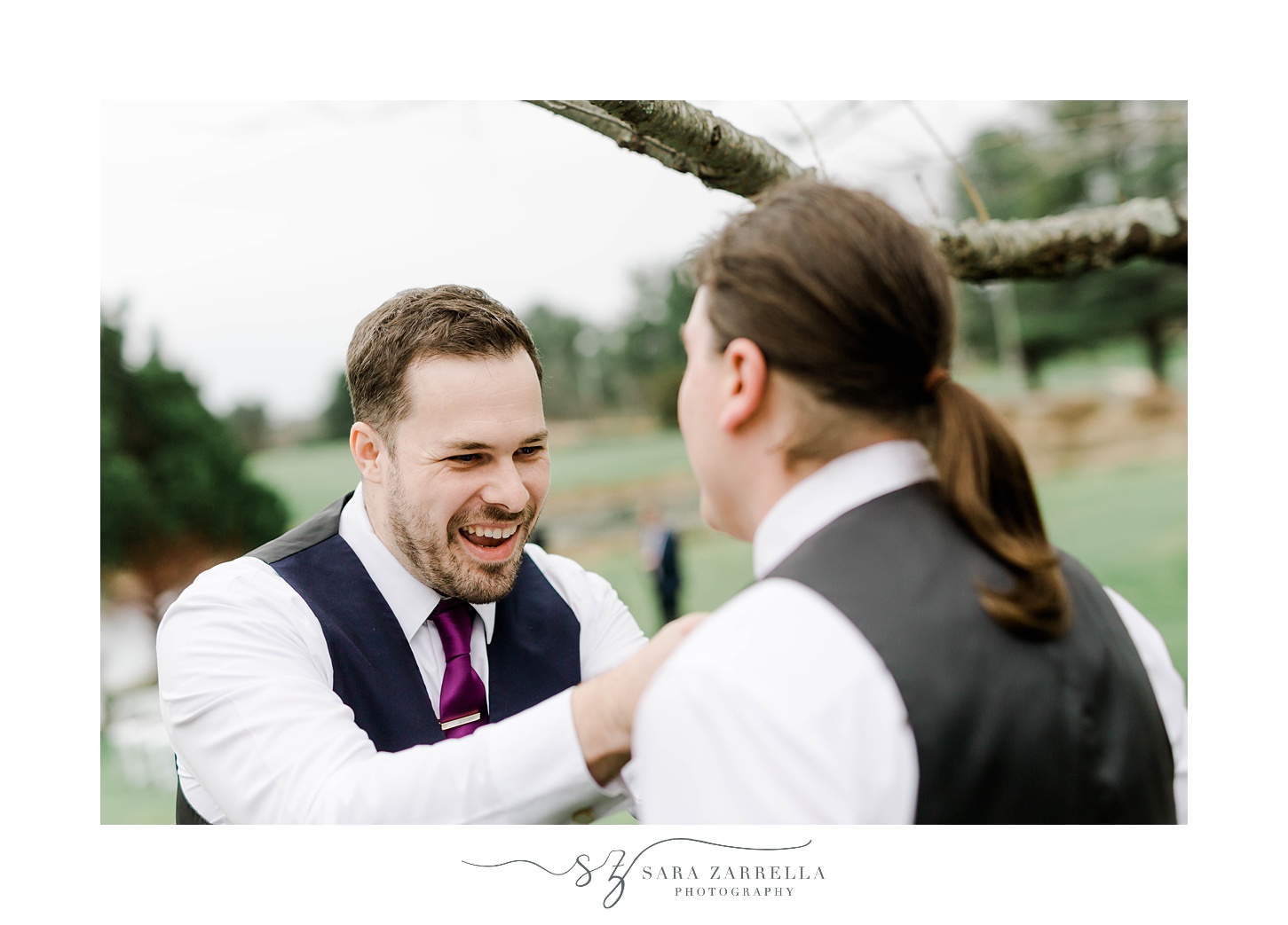 groomsman helps groom with tie on wedding day 