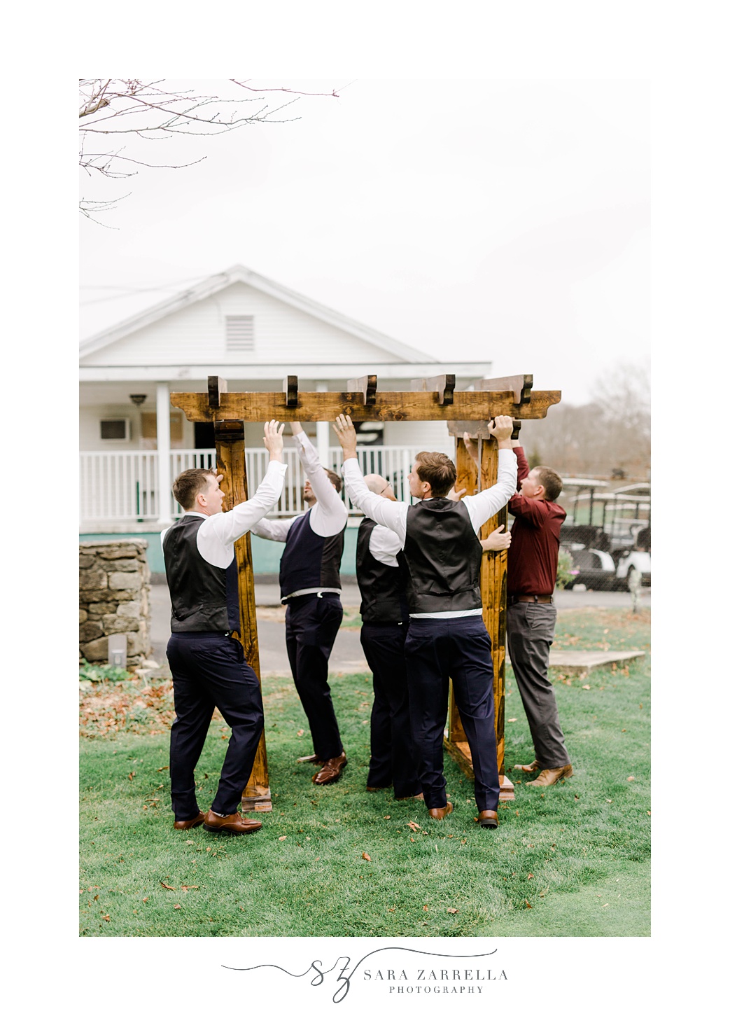 groom and groomsmen lift up wooden arbor for ceremony at Foster Country Club