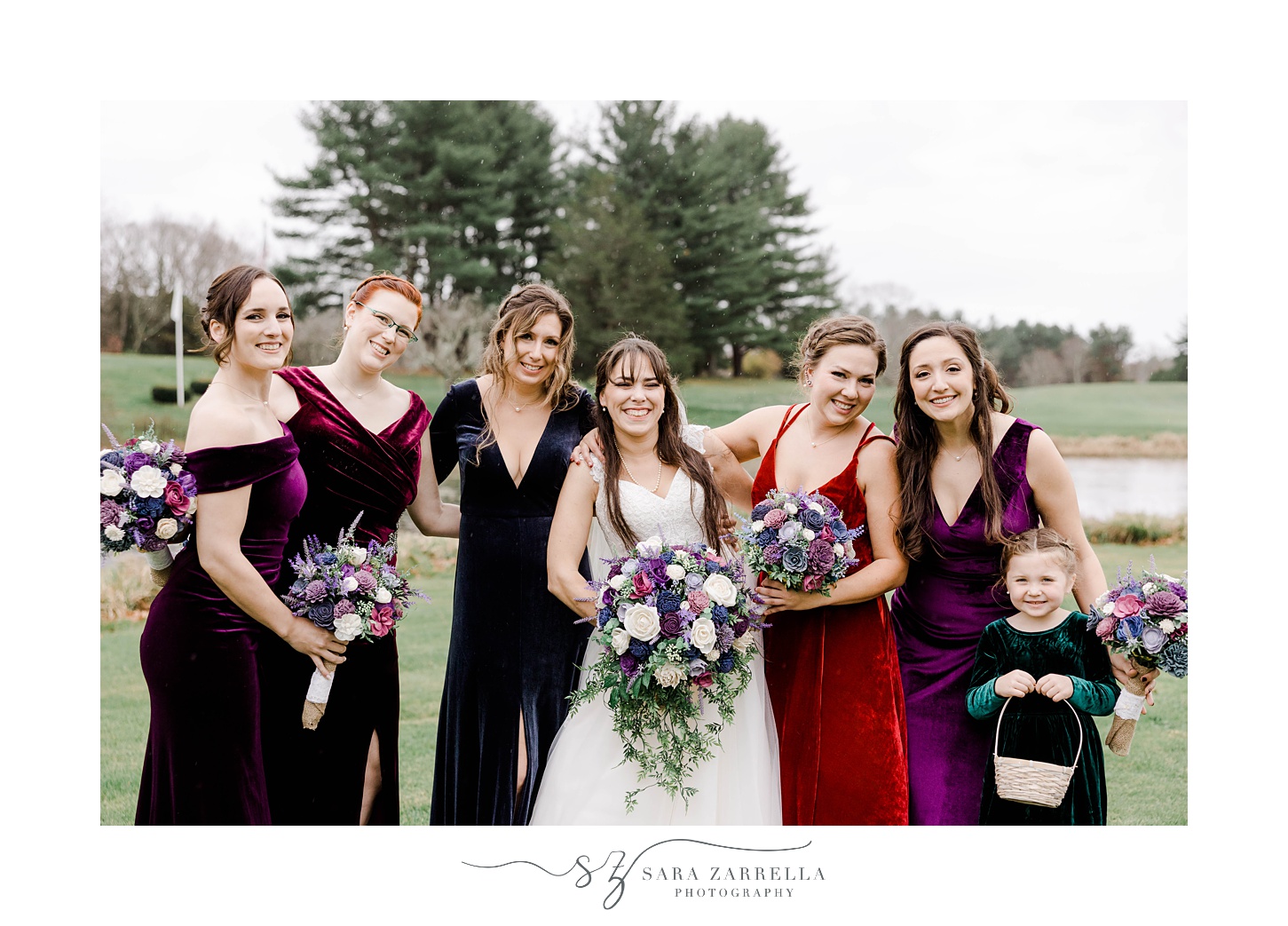 bride poses with bridesmaids in jewel tone velvet dresses for fall wedding 