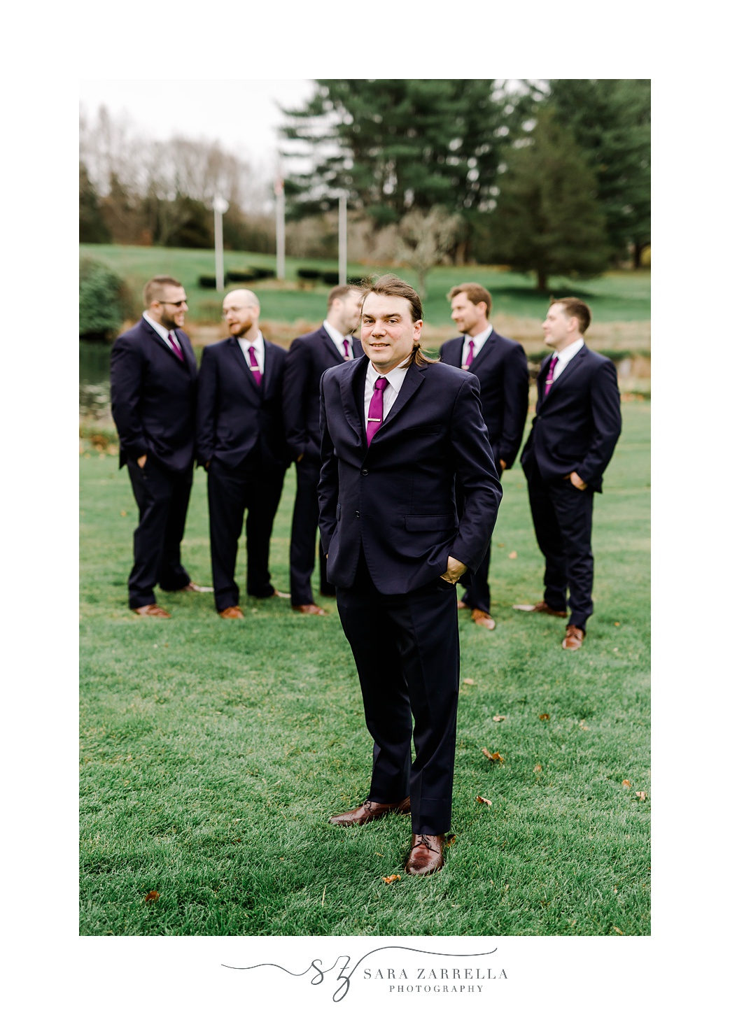 groom and groomsmen stand with hands in pockets of black suits 