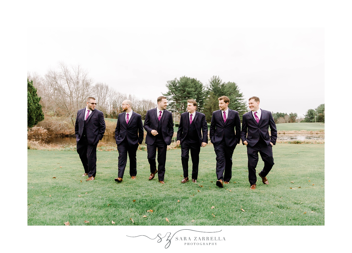 groom walks with groomsmen in black suits across lawn at Foster Country Club
