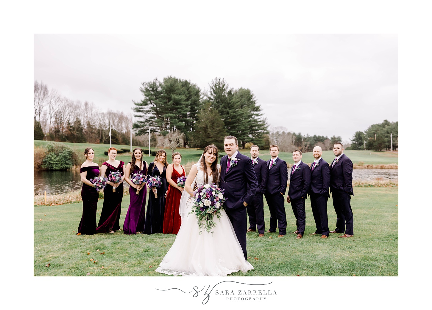 bride and groom stand with wedding party in jewel-tones
