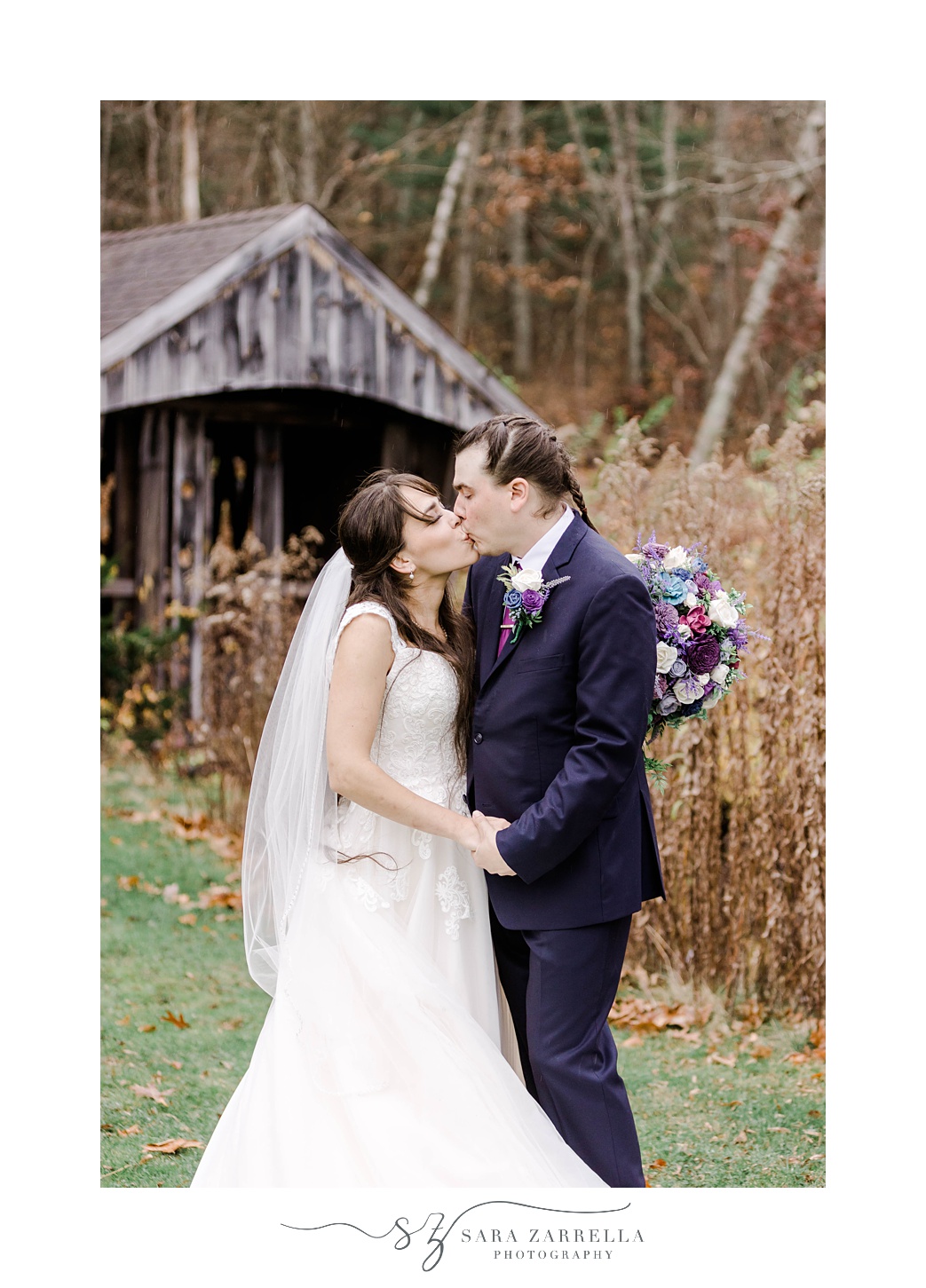 newlyweds kiss near wooden covered bridge 