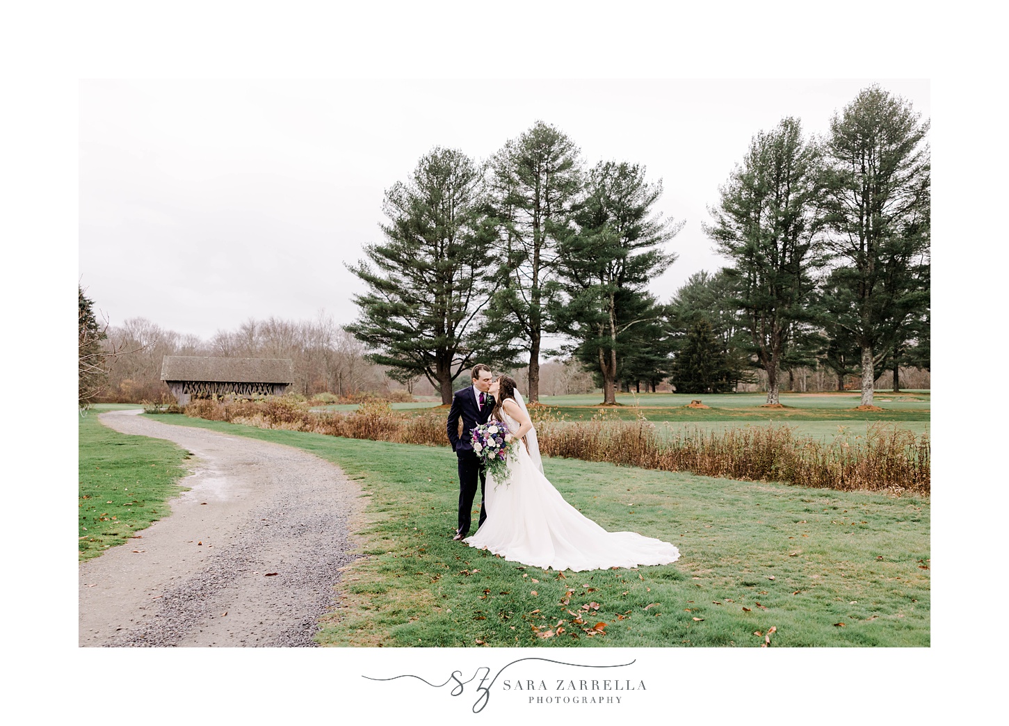 newlyweds hug by dirt road on lawn at Foster Country Club