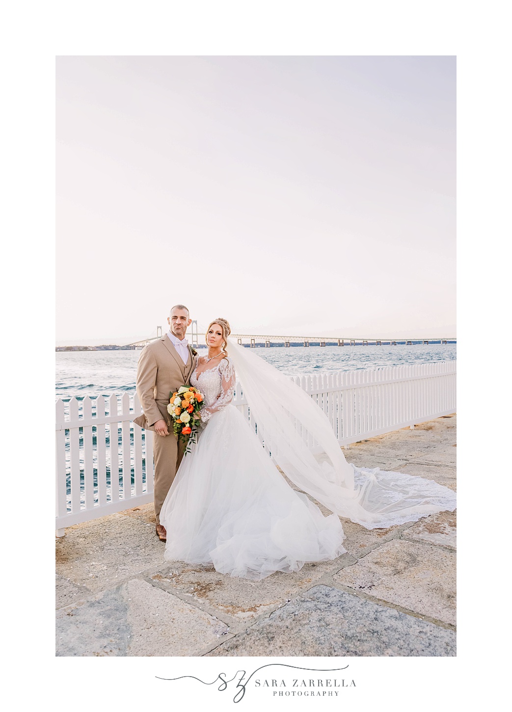 newlyweds pose along white fence at Newport Harbor Island Resort