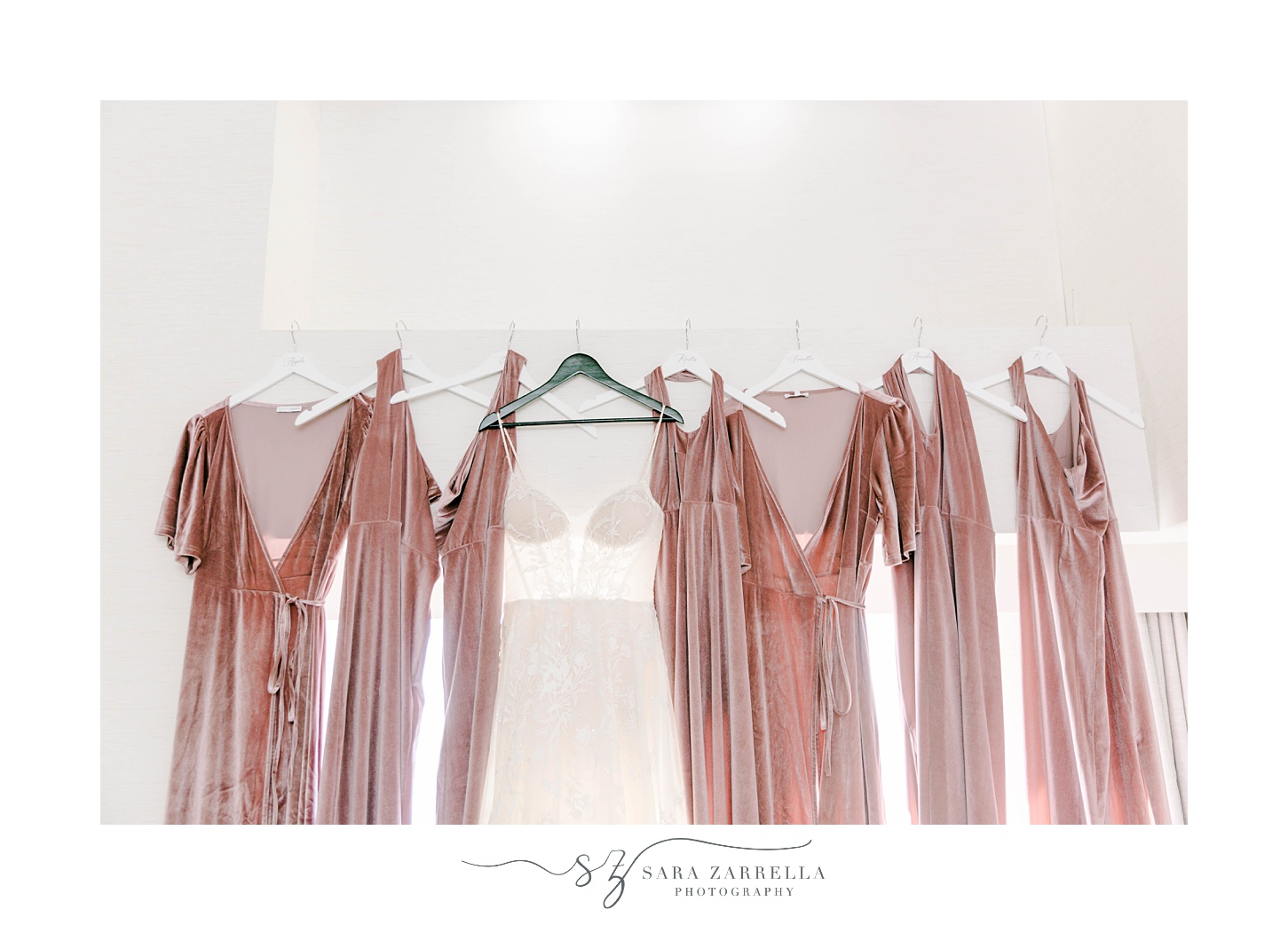 bride's dress hangs with pink bridesmaid gowns