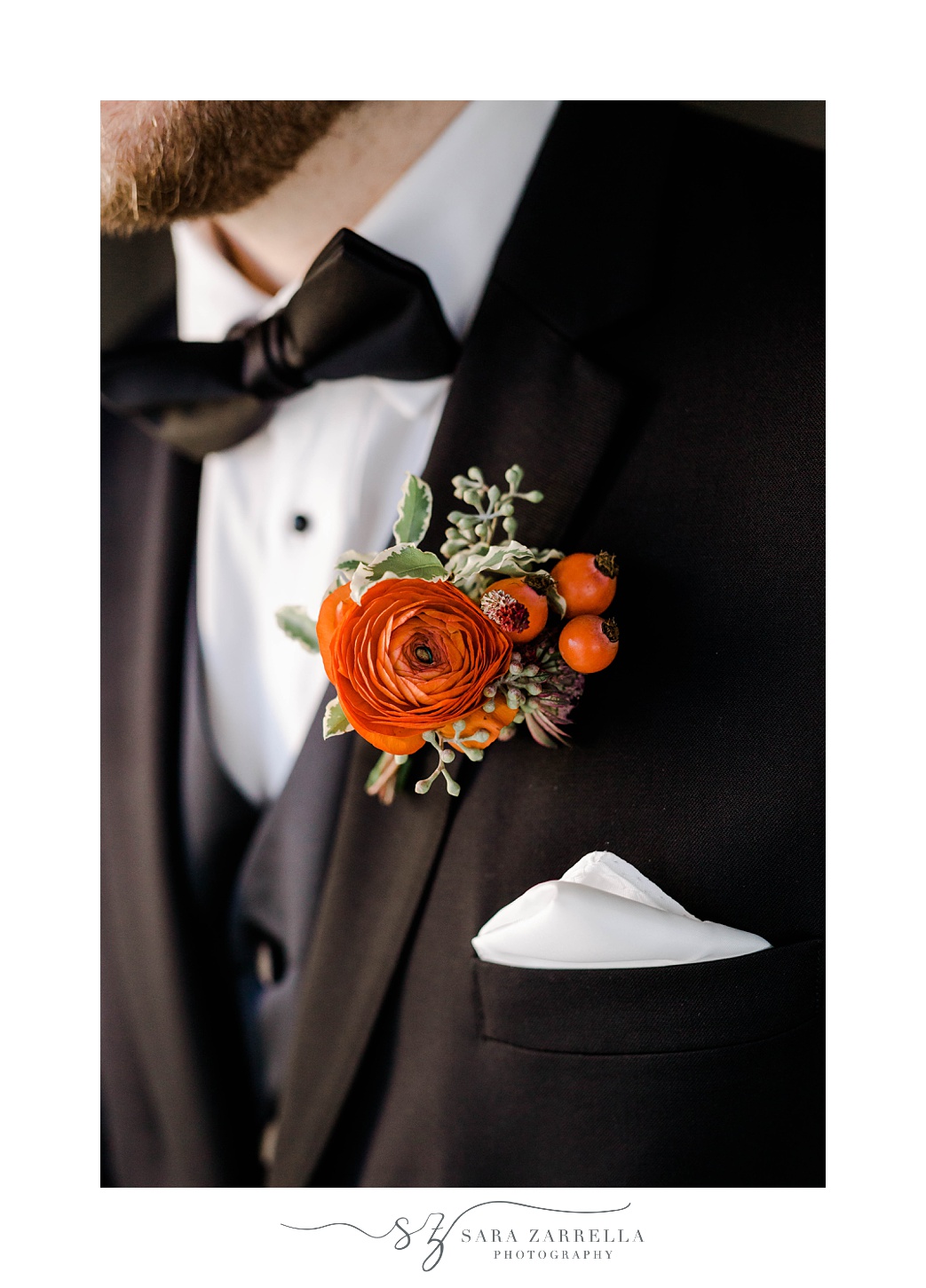 groom in black tux with orange floral boutonnière