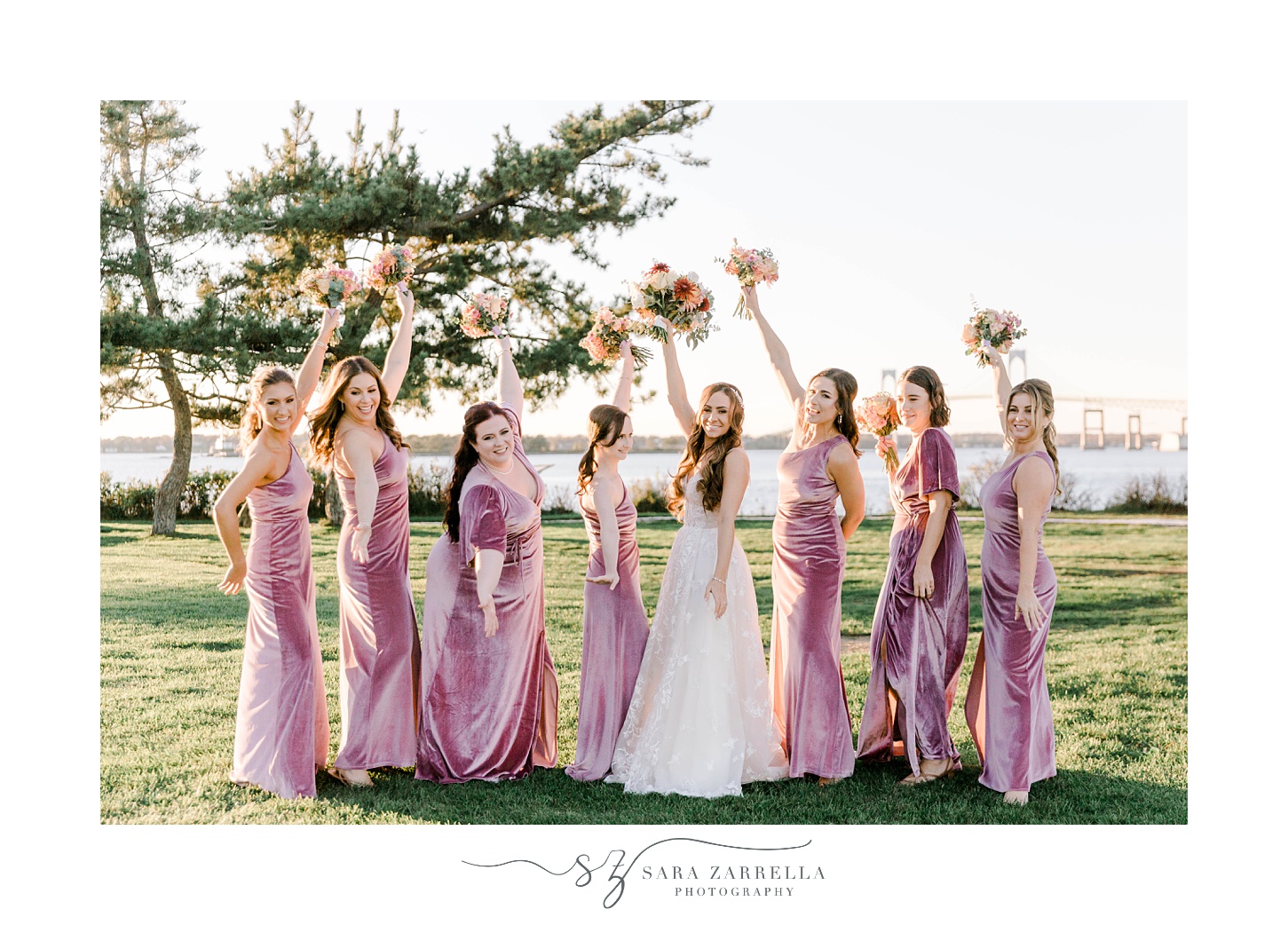 bride and bridesmaids in pink gowns lift bouquets in the air
