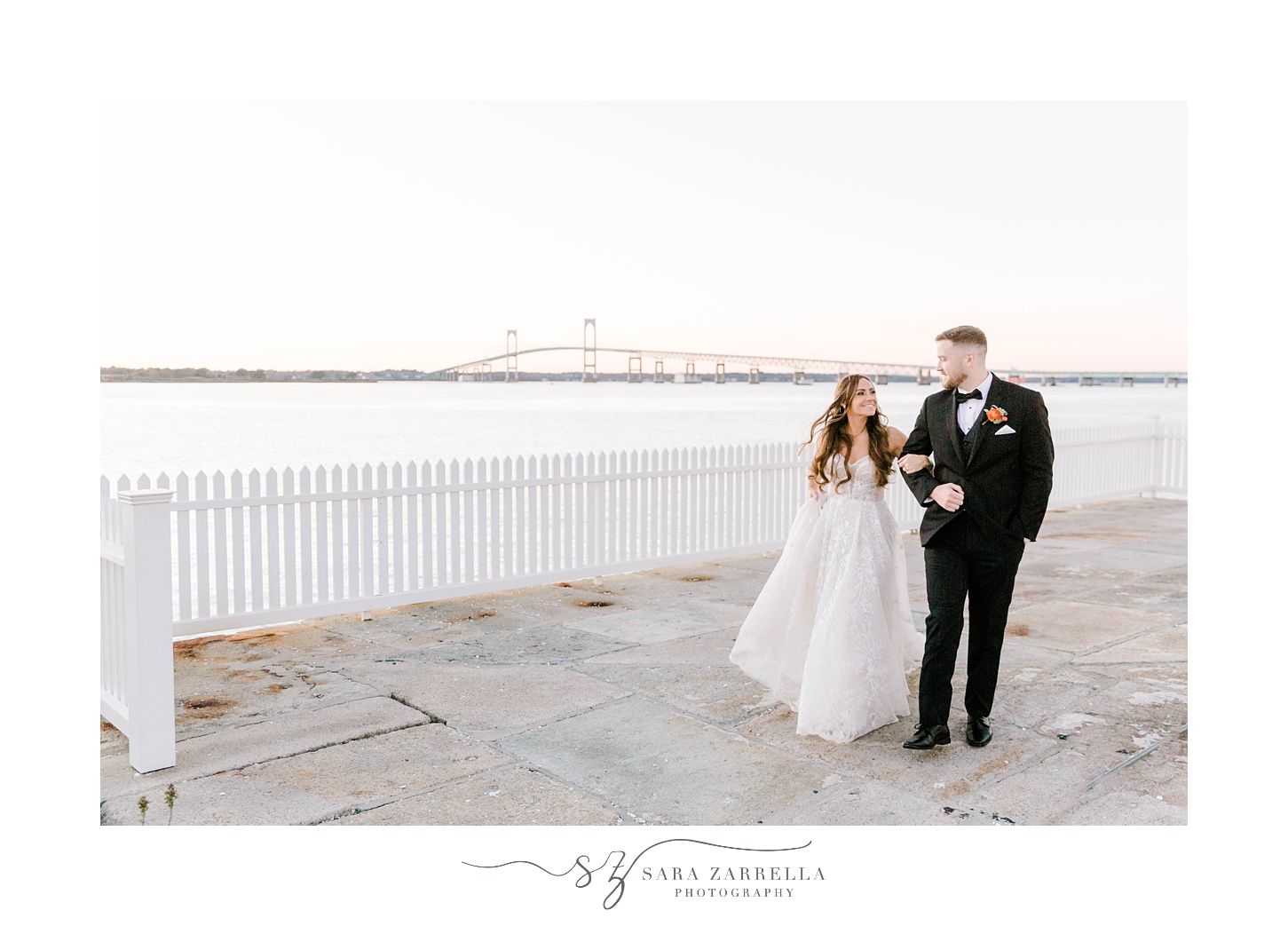 newlyweds hold hands walking along bridge at Newport Harbor Island Resort