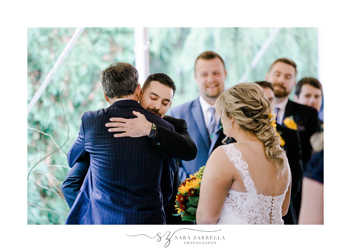 groom hugs father of bride during fall ceremony at Quidnessett Country Club