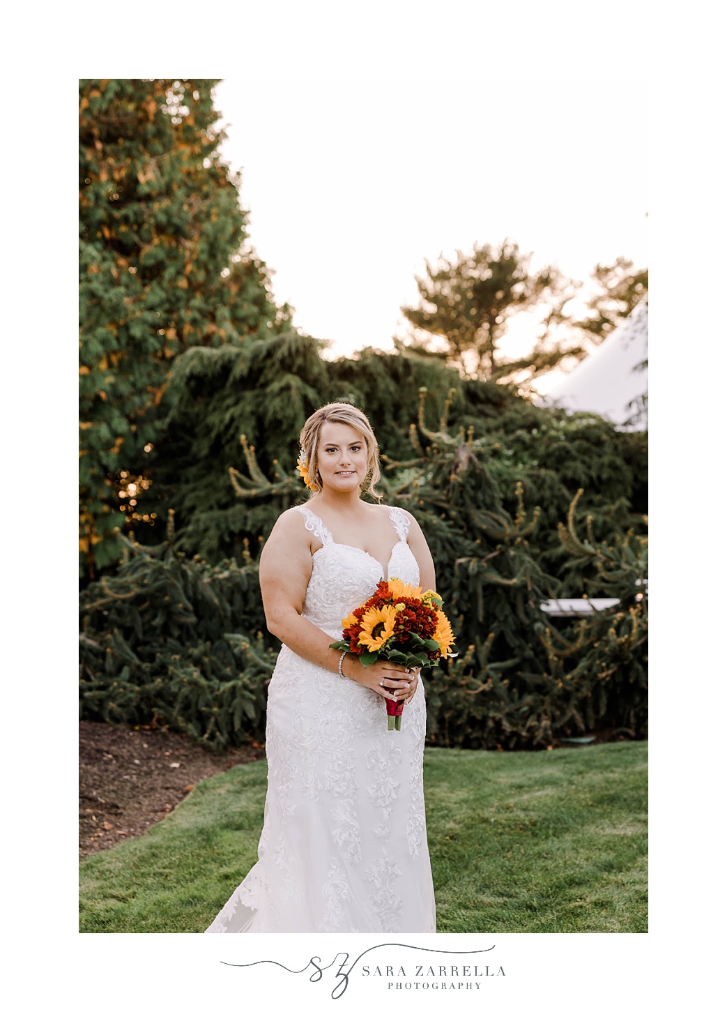 bride stands holding fall bouquet of sunflowers at Quidnessett Country Club