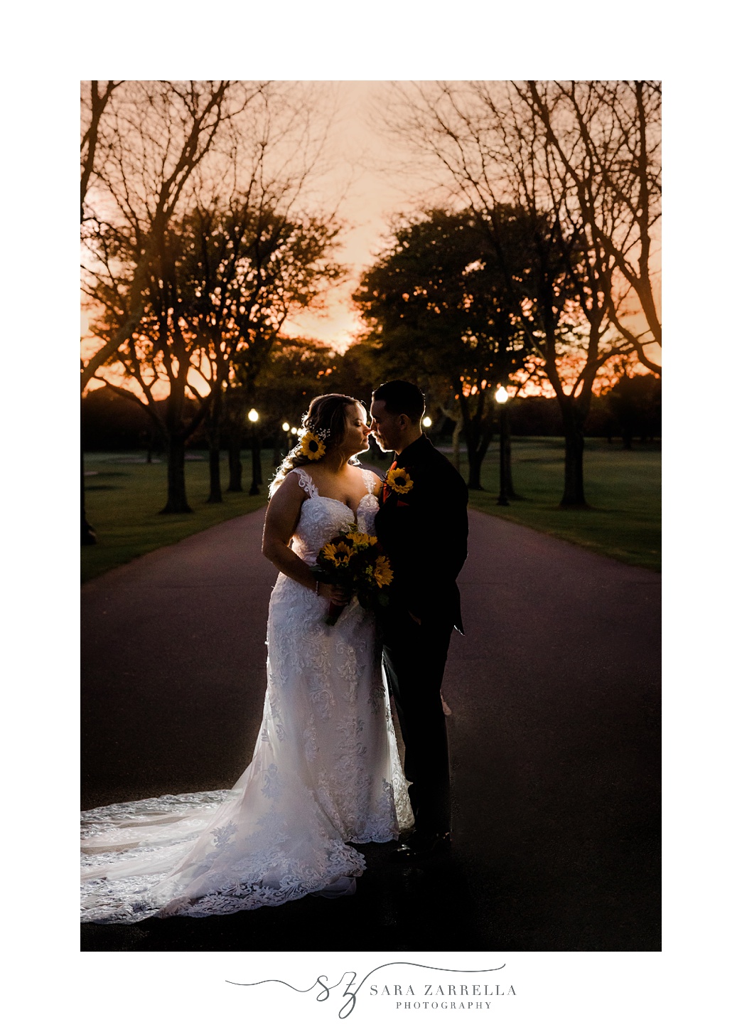 bride and groom kiss during sunset portraits on driveway at Quidnessett Country Club