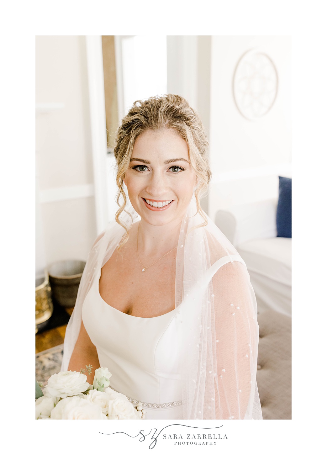 bride sits in classic wedding gown with veil around shoulders 
