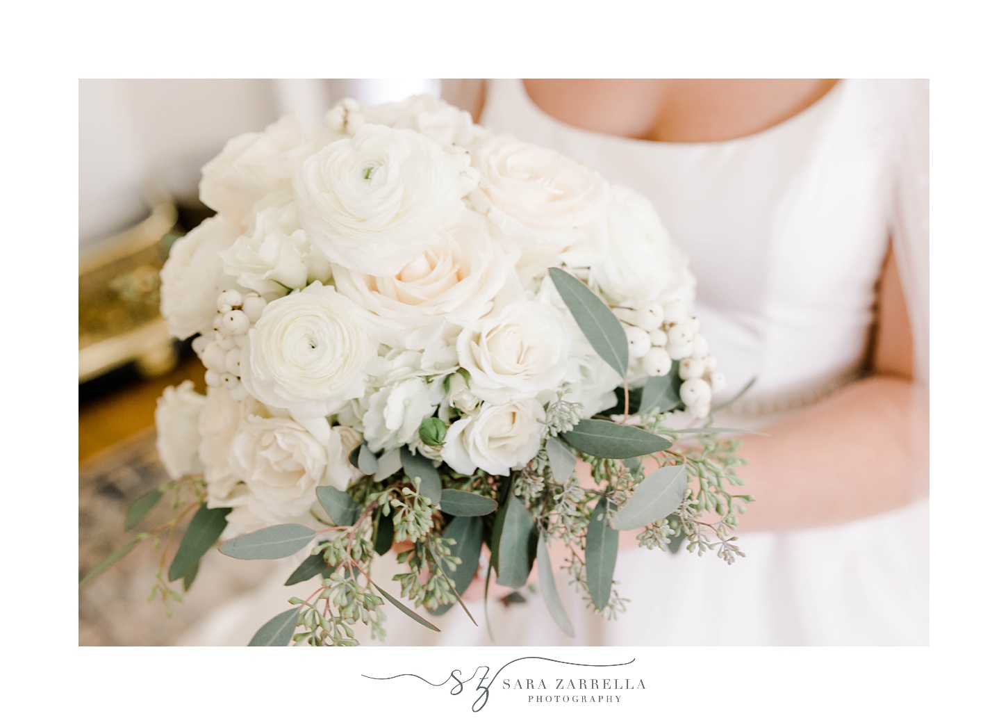 bride sits holding bouquet of white roses and flowers 