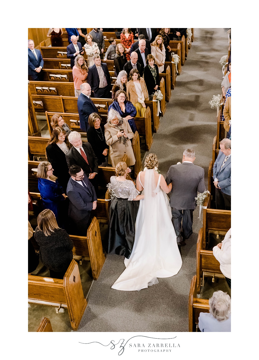 parents walk bride between wooden pews in church 