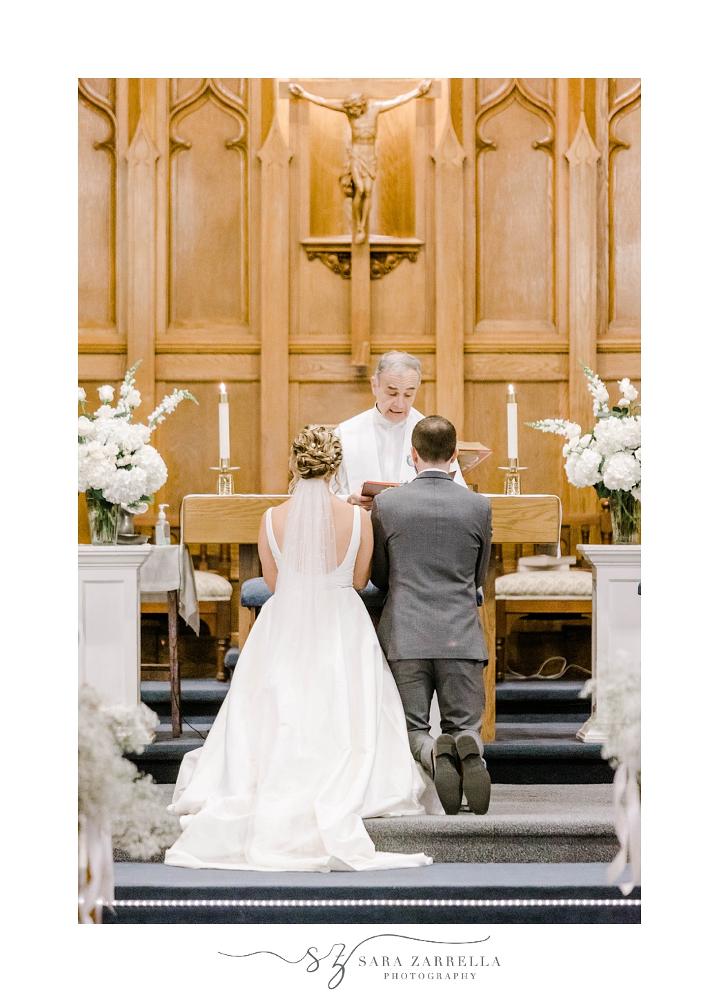 newlyweds kneel during  traditional church ceremony in Rhode Island 