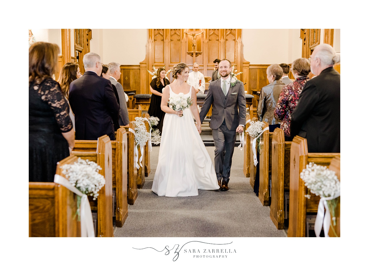 bride and groom hold hands walking up aisle after  traditional church ceremony in Rhode Island 