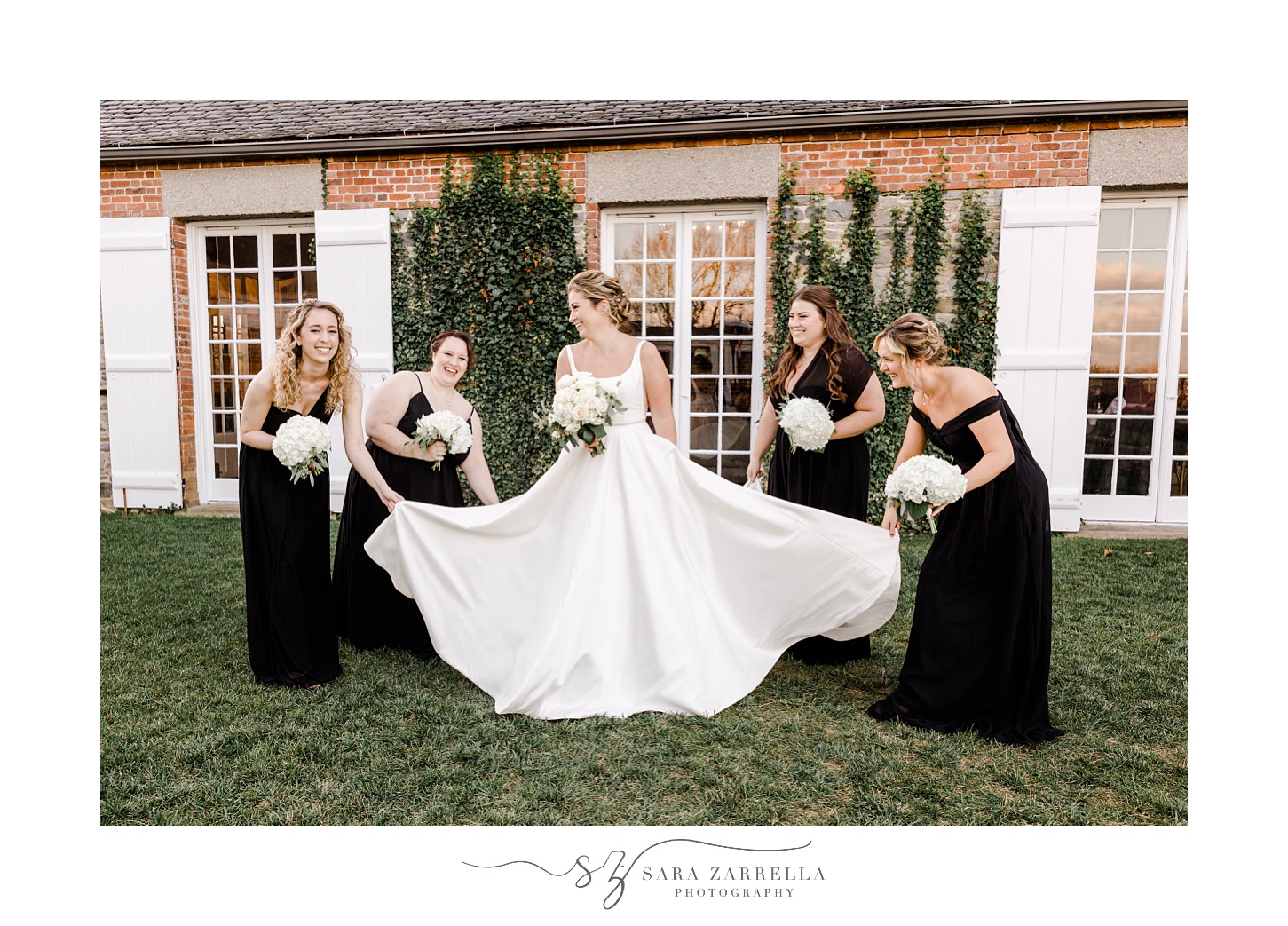 bridesmaids in black gowns help adjust bride's dress