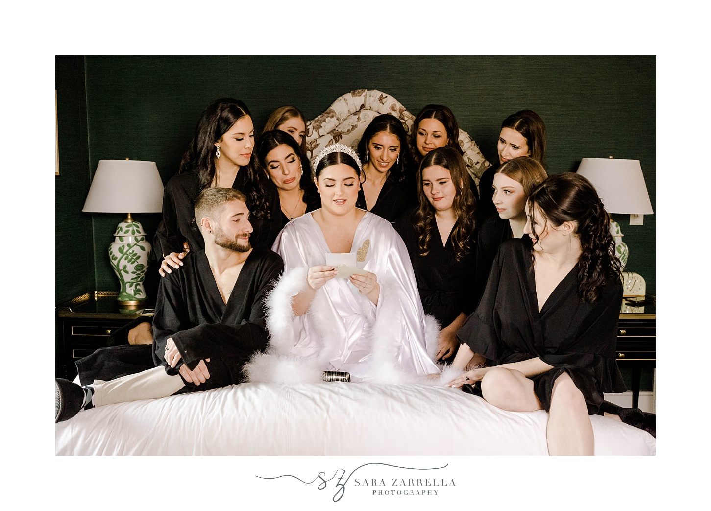 bride sits on bed with bridal party in black robes