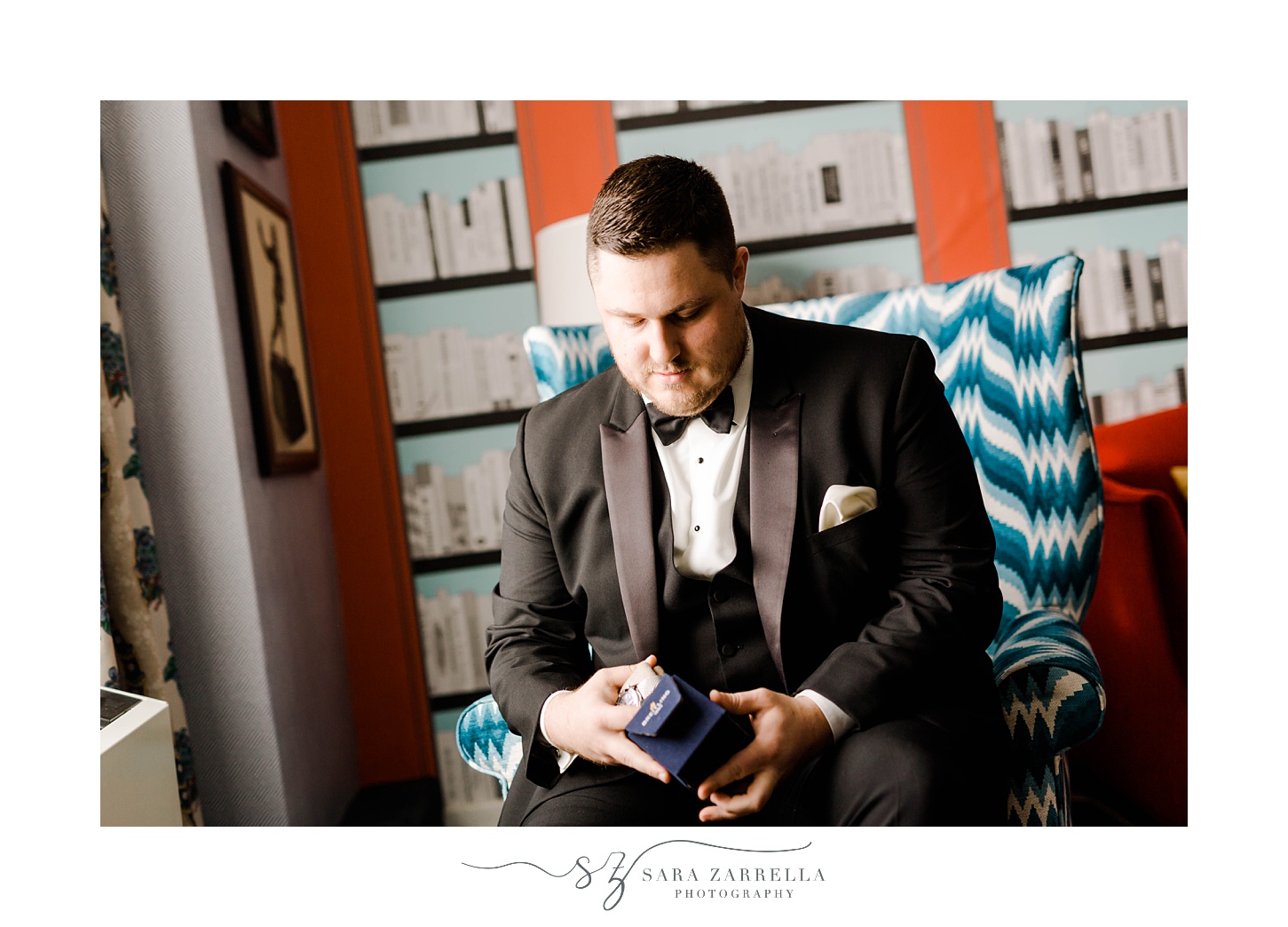 groom opens gift sitting in blue and white chair 