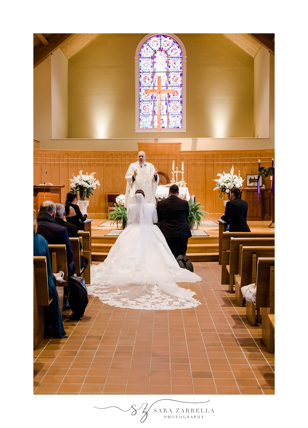 bride and groom kneel during traditional church wedding in Providence, RI