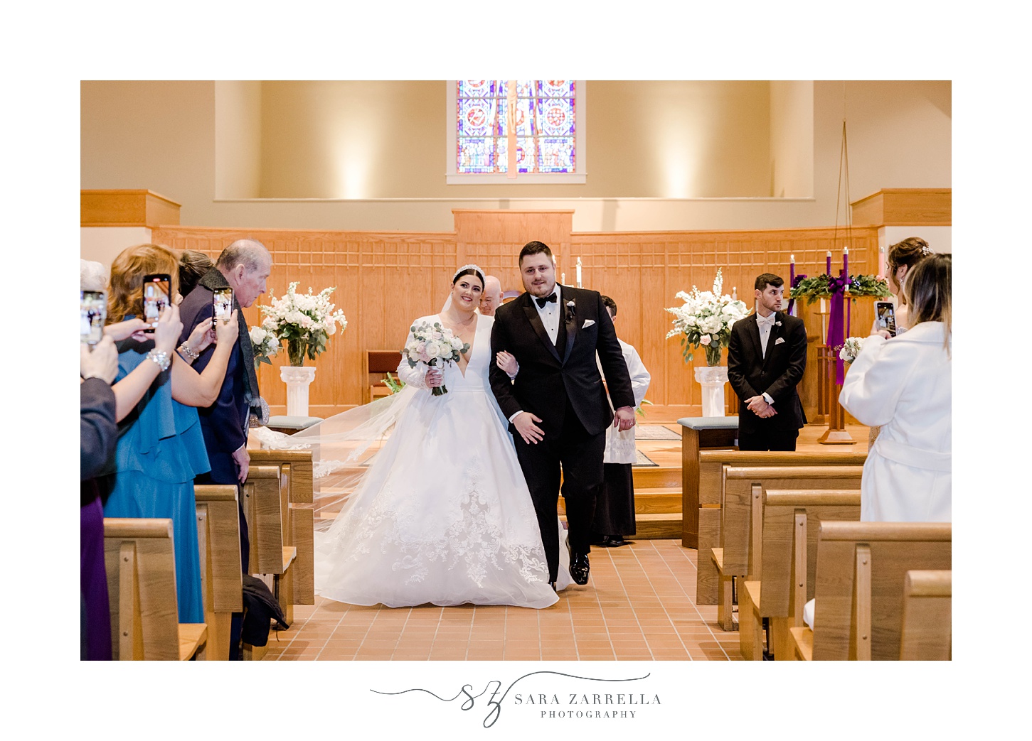 bride and groom smile turning to face guests after traditional church wedding in Providence, RI