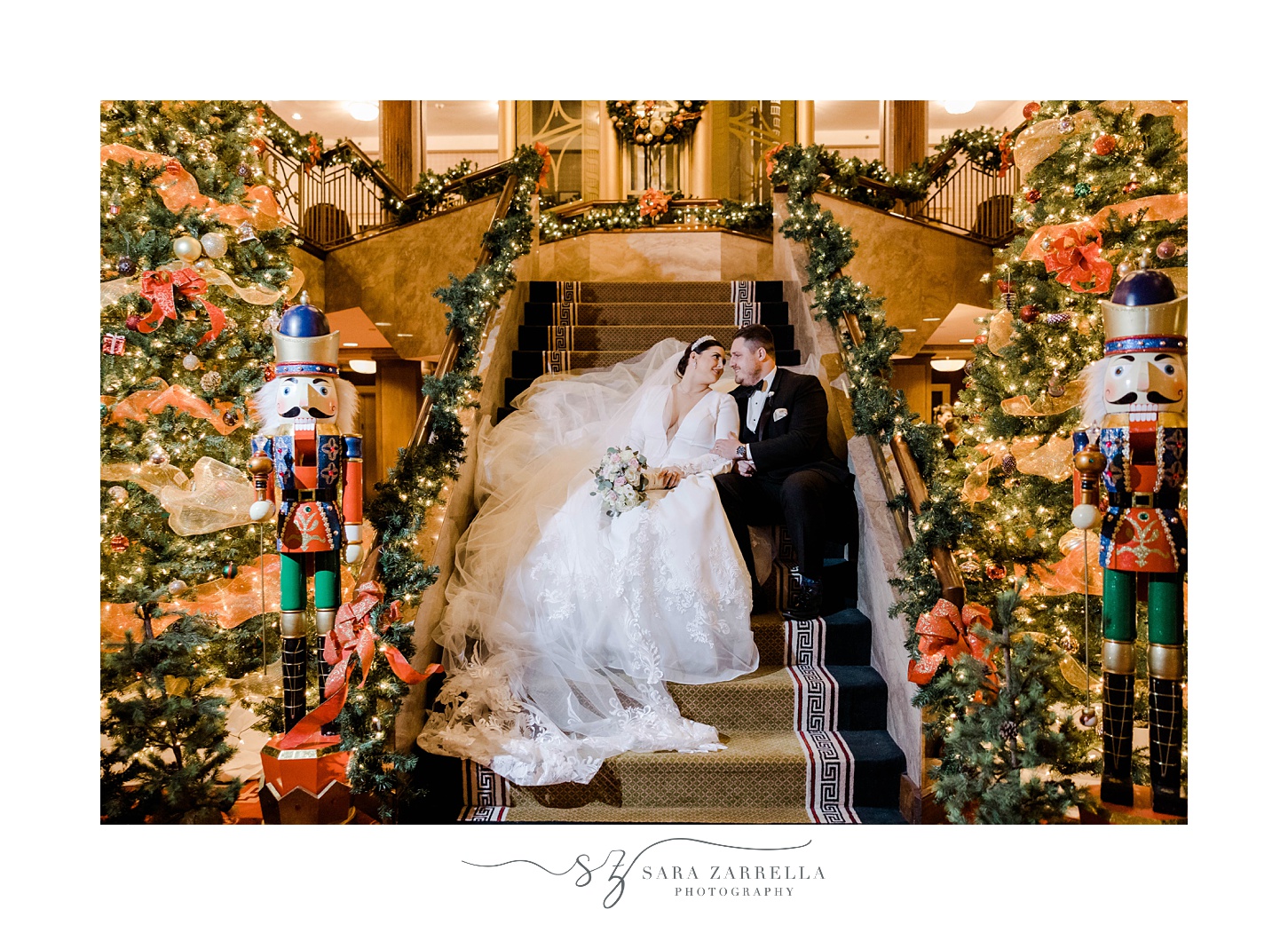 bride and groom pose on steps with Christmas decor around them at The Graduate Providence
