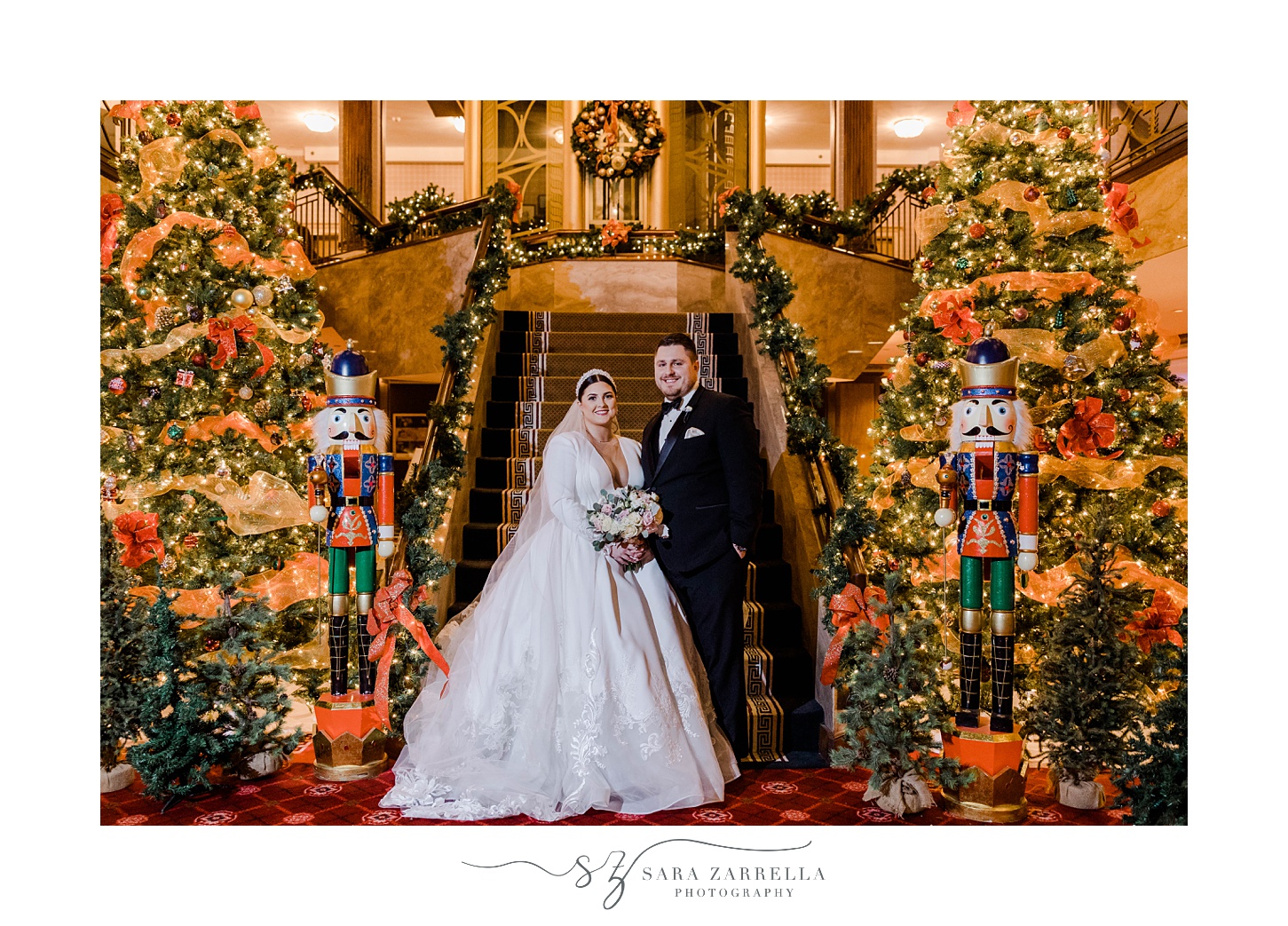 bride and groom stand on staircase surrounded by Christmas decorations at The Graduate Providence