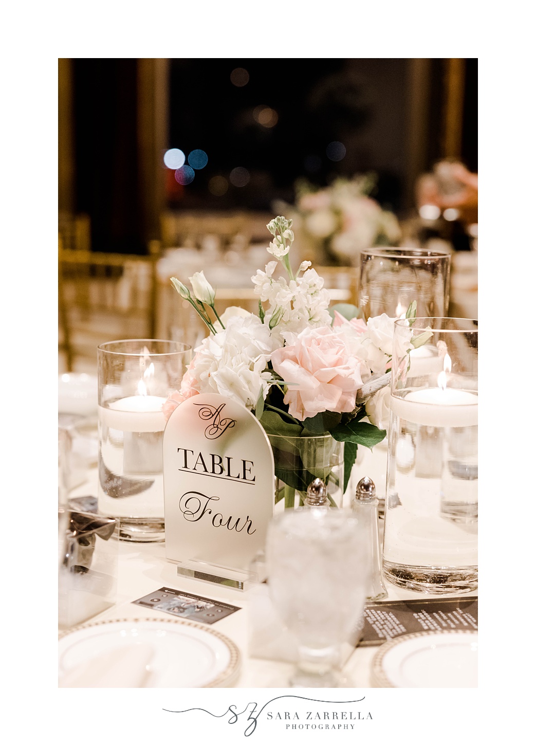 table numbers rest against pink and white rose centerpiece 