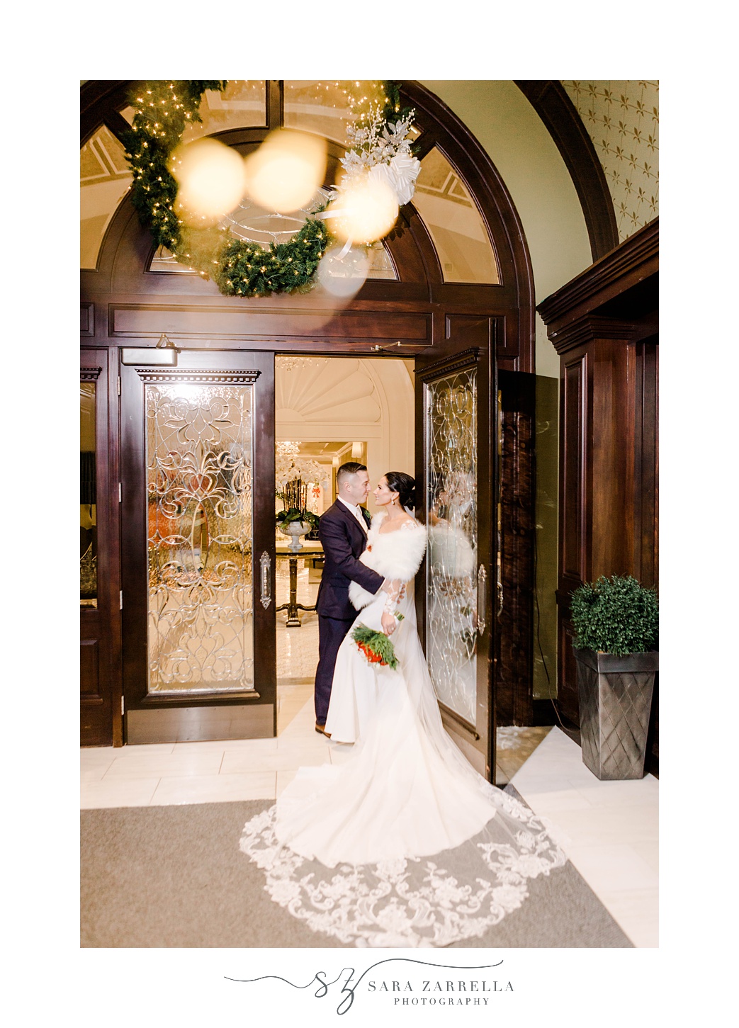 bride and groom hug against glass door of Quidnessett Country Club