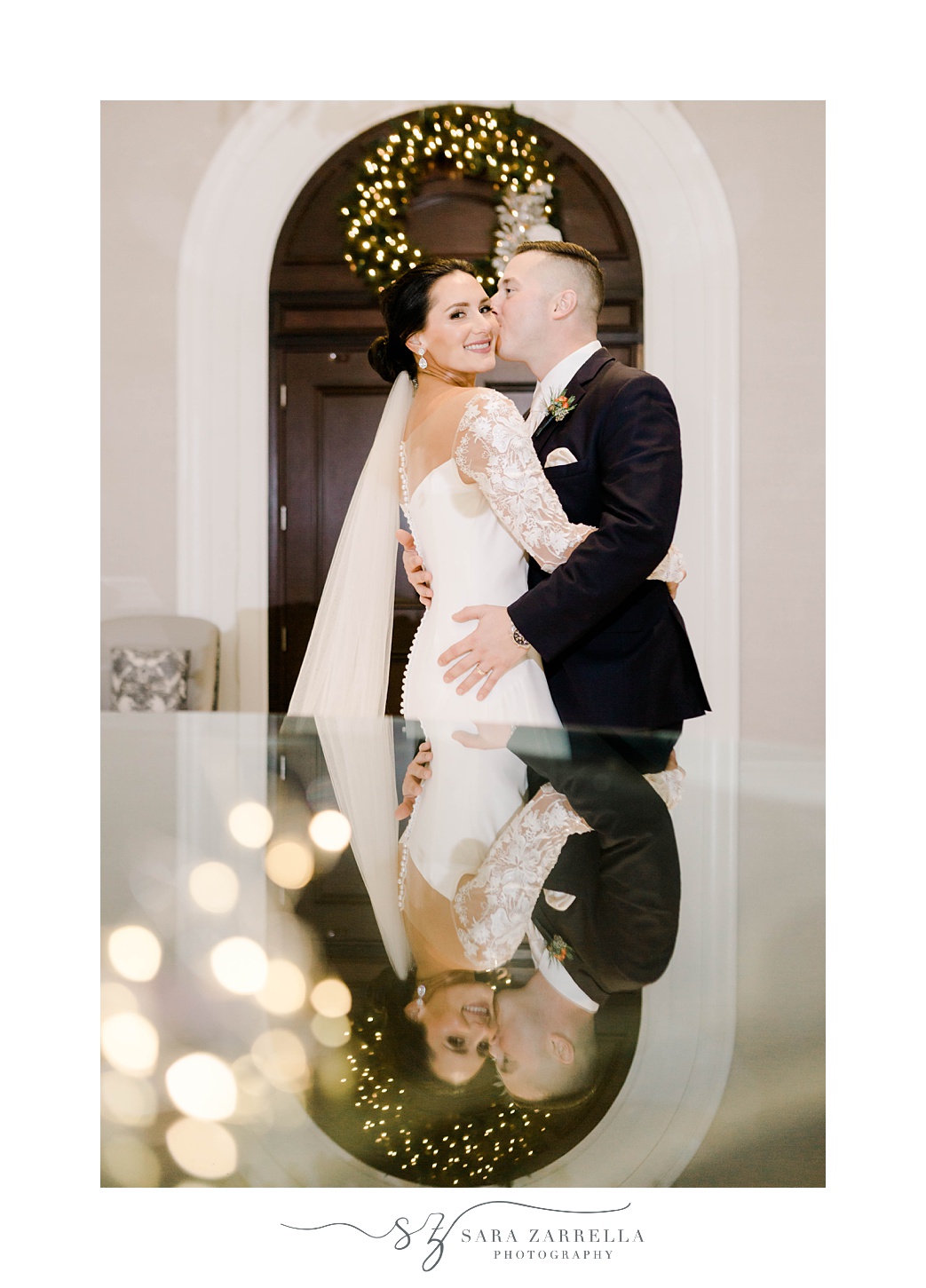 groom kisses bride's cheek beside glass table at Quidnessett Country Club