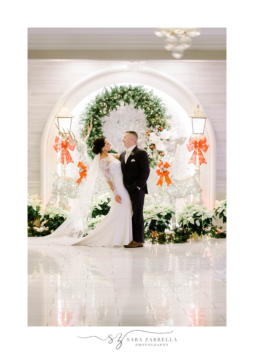 bride and groom hug by Christmas decor and wreath at Quidnessett Country Club