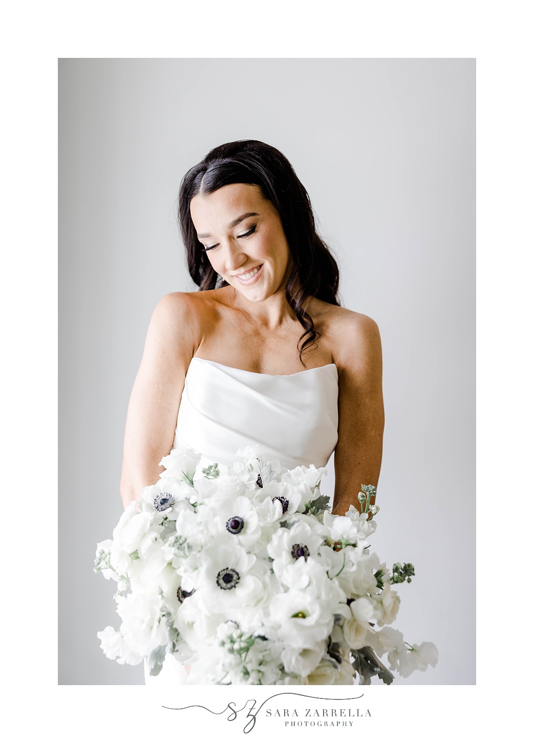 bride in strapless wedding gown holds bouquet of anemones