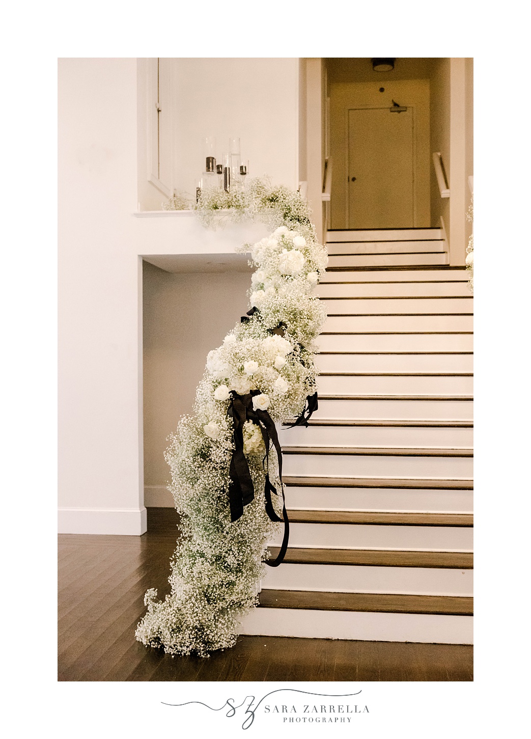 white roses and baby's breath up stairs inside The Salon at Belle Mer