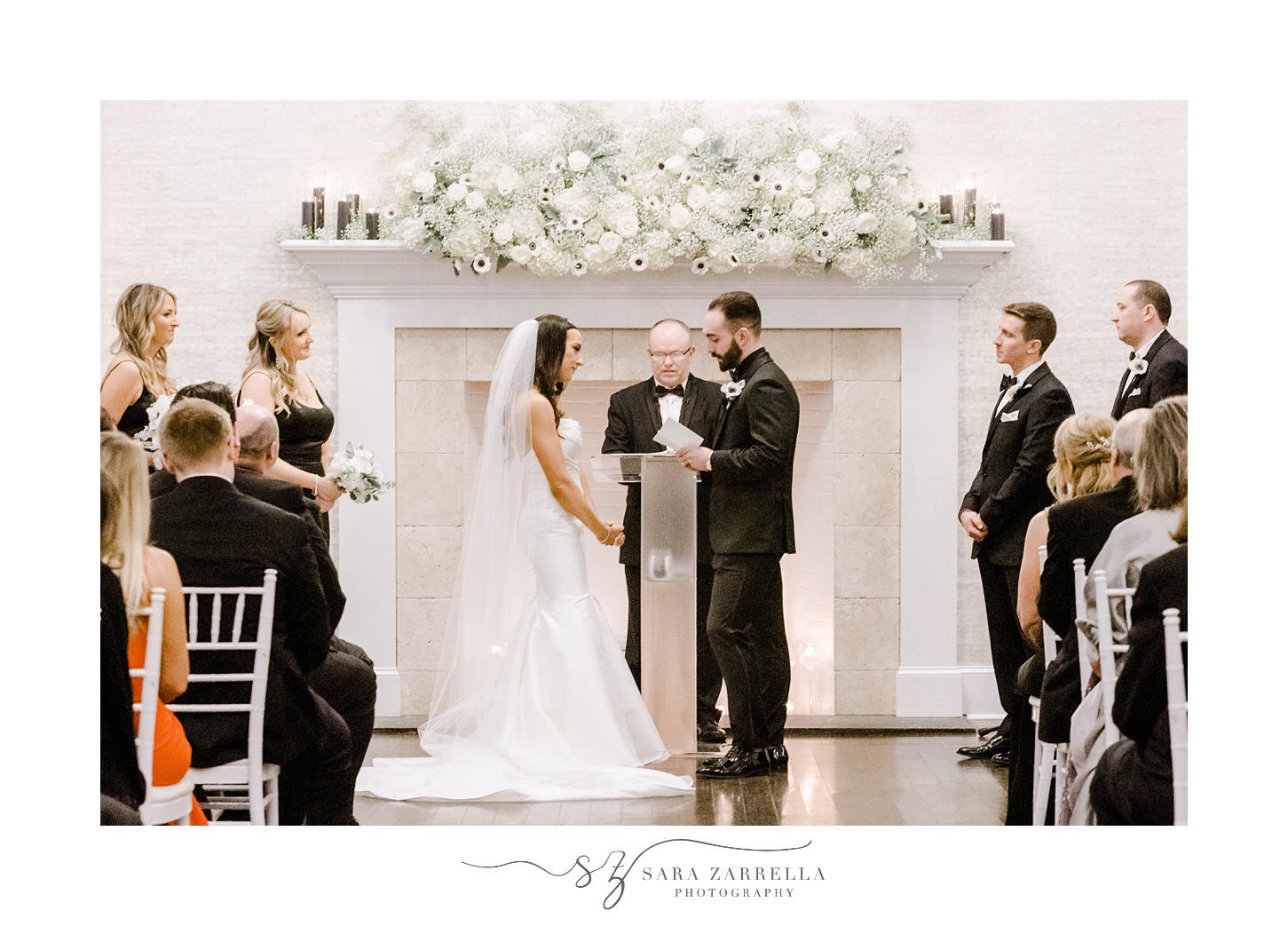 bride and groom exchange vows by fireplace at The Salon at Belle Mer