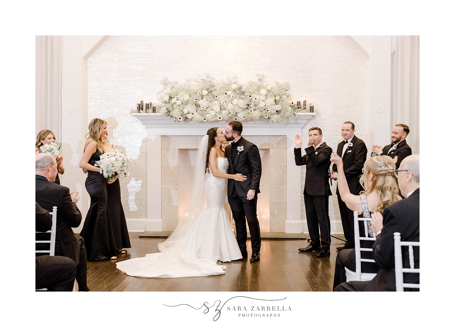 newlyweds kiss in front of fireplace during ceremony at The Salon at Belle Mer