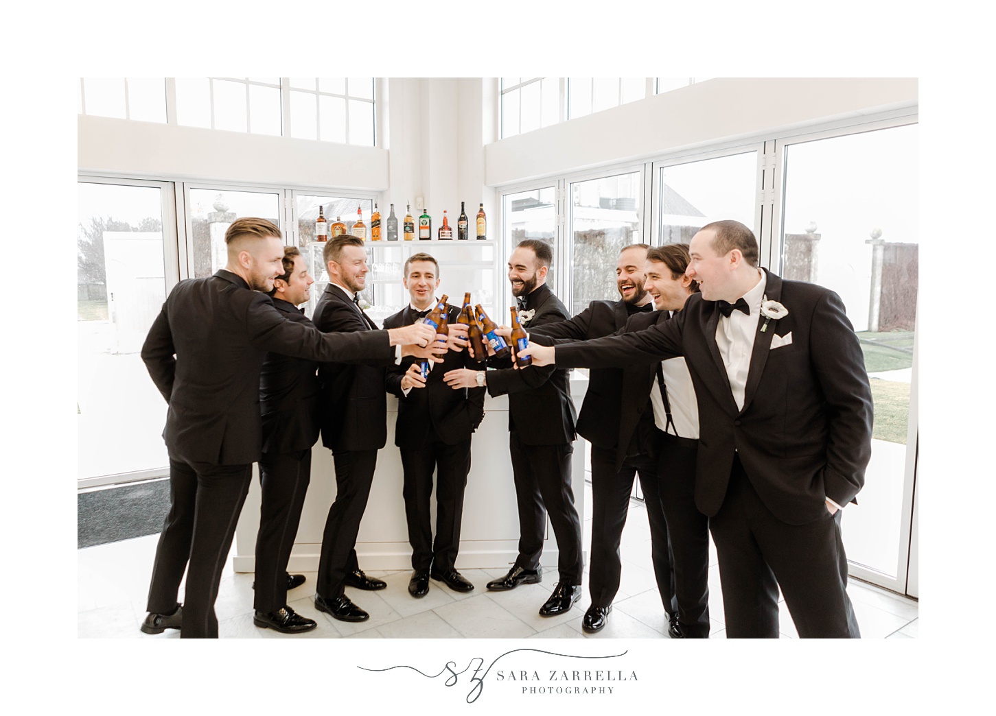 groom toasts with groomsmen at bar in corner of windows at Belle Mer 