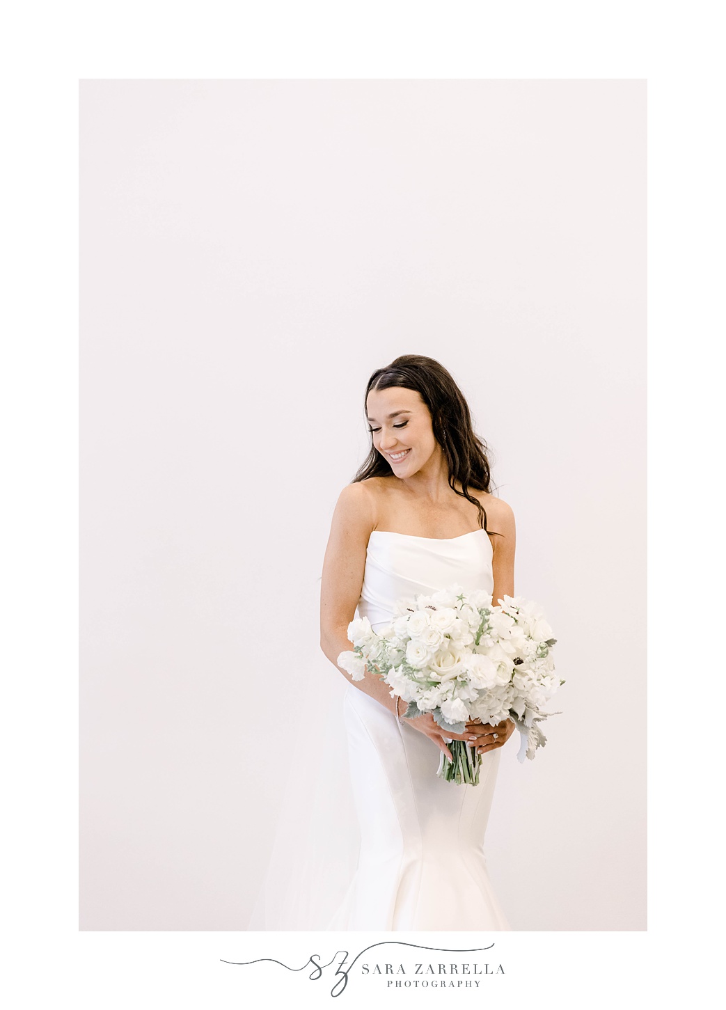 bride laughs in strapless gown holding bouquet of white anemones