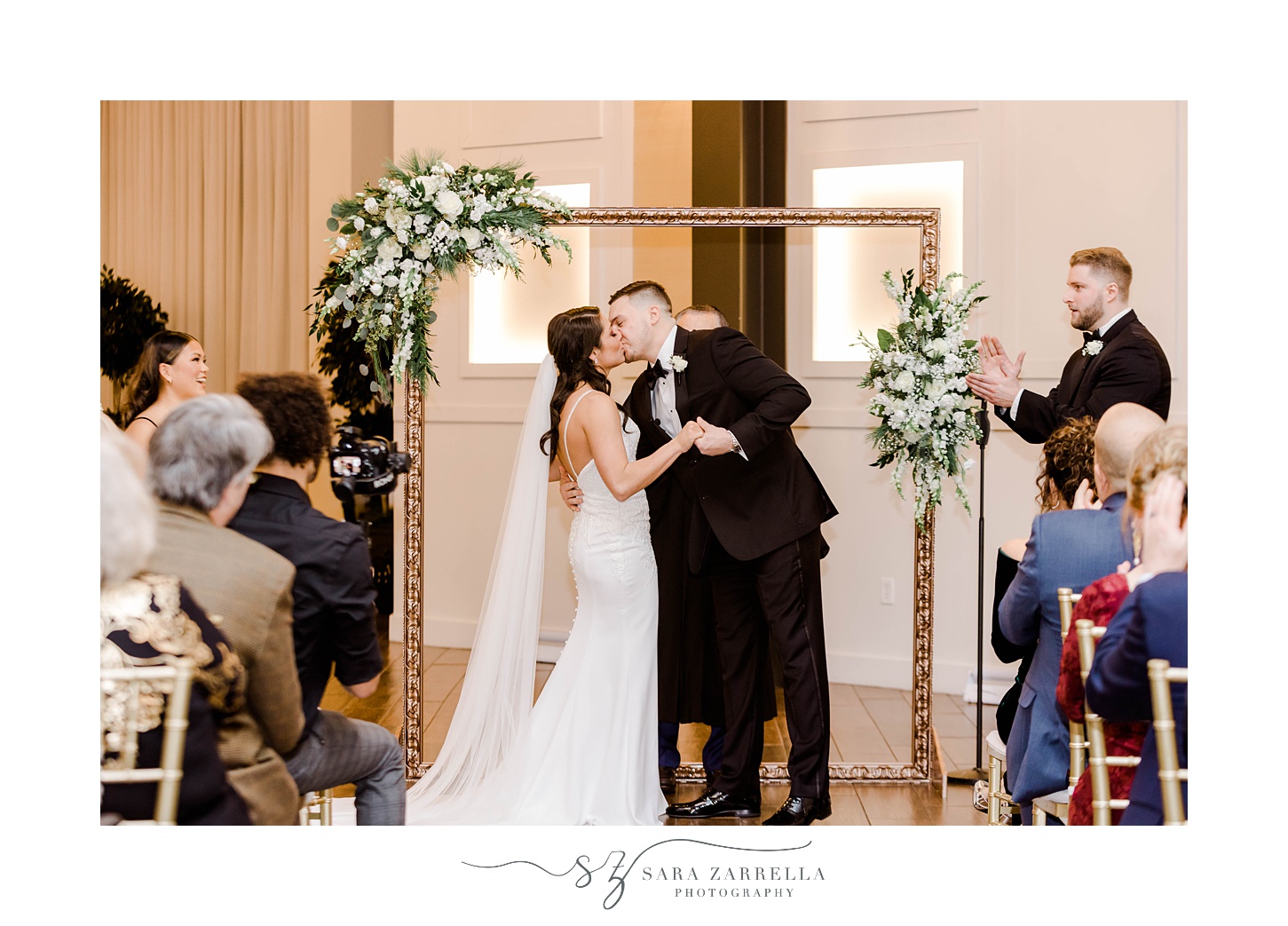 bride and groom kiss under gold arbor in the atrium at the Crowne Plaza