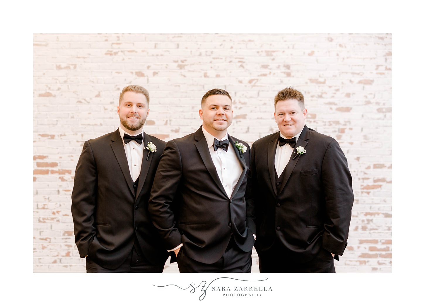 groom stands with groomsmen against brick wall inside the Crowne Plaza Warwick