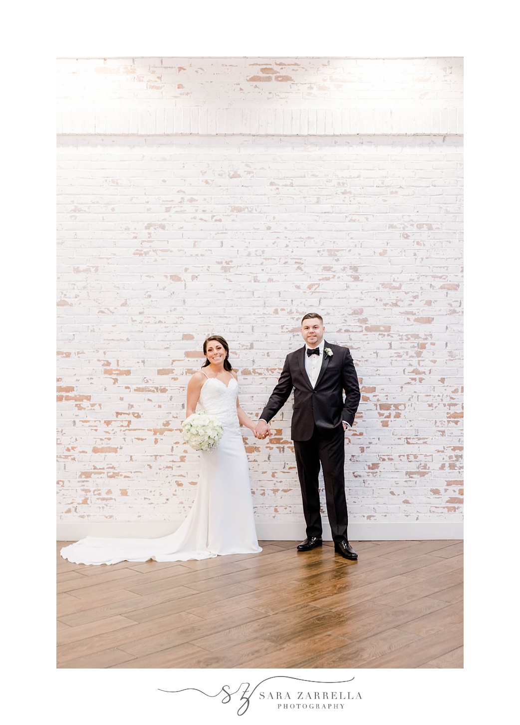 bride and groom hold hands by brick wall inside the Crowne Plaza Warwick