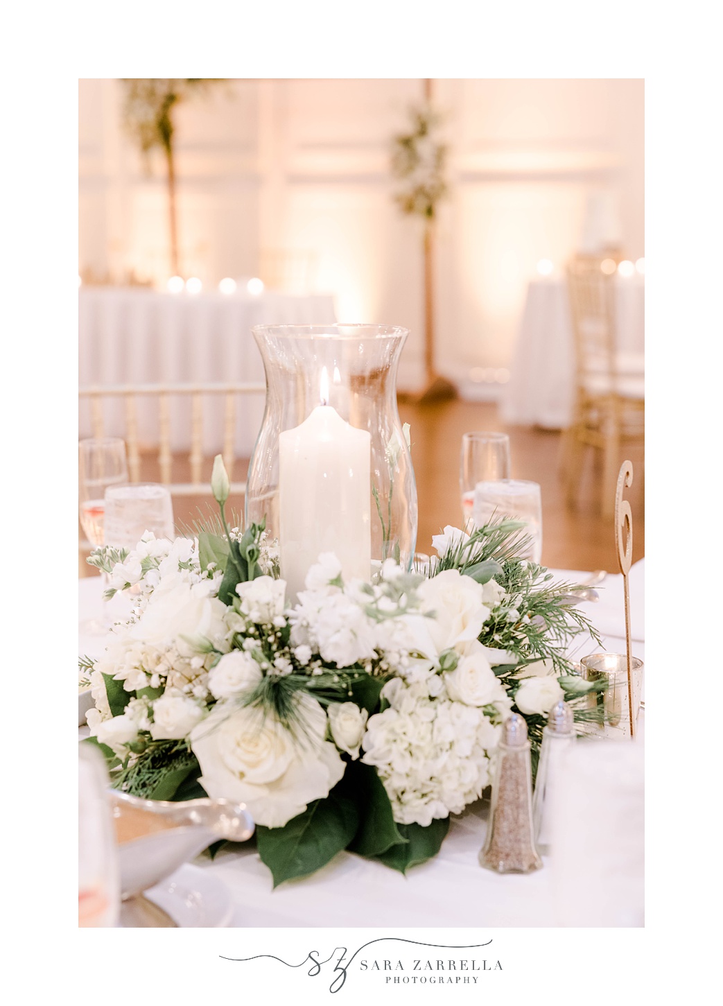 tall candle sits in middle of ivory flowers for winter wedding reception 