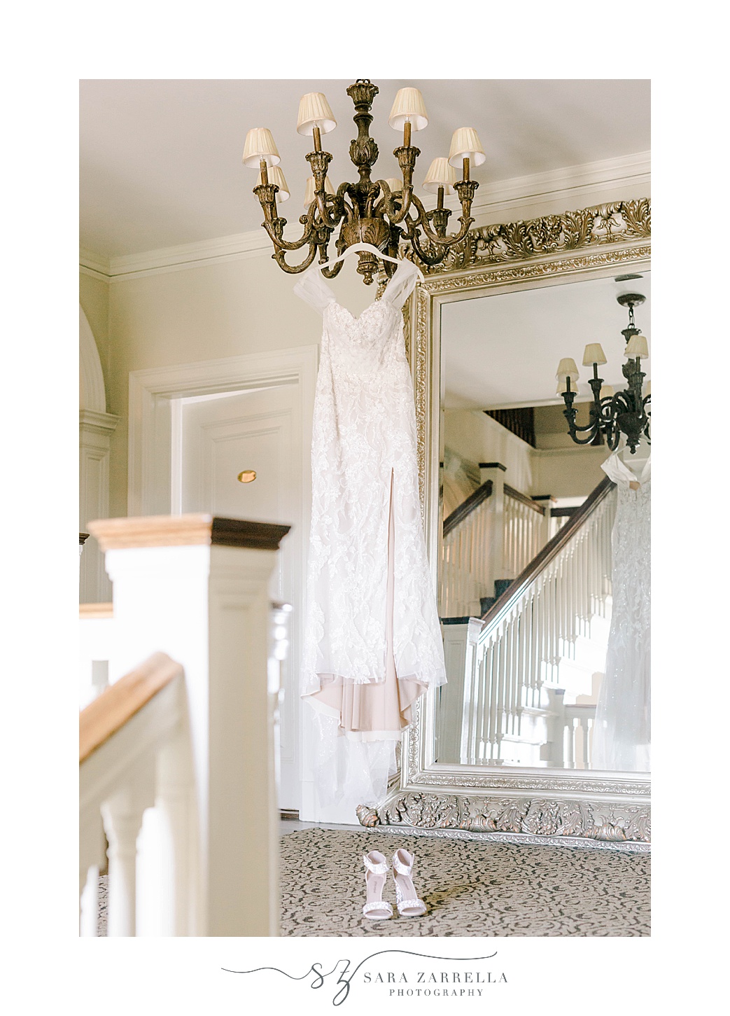 bride's wedding dress hangs from chandelier at OceanCliff Hotel