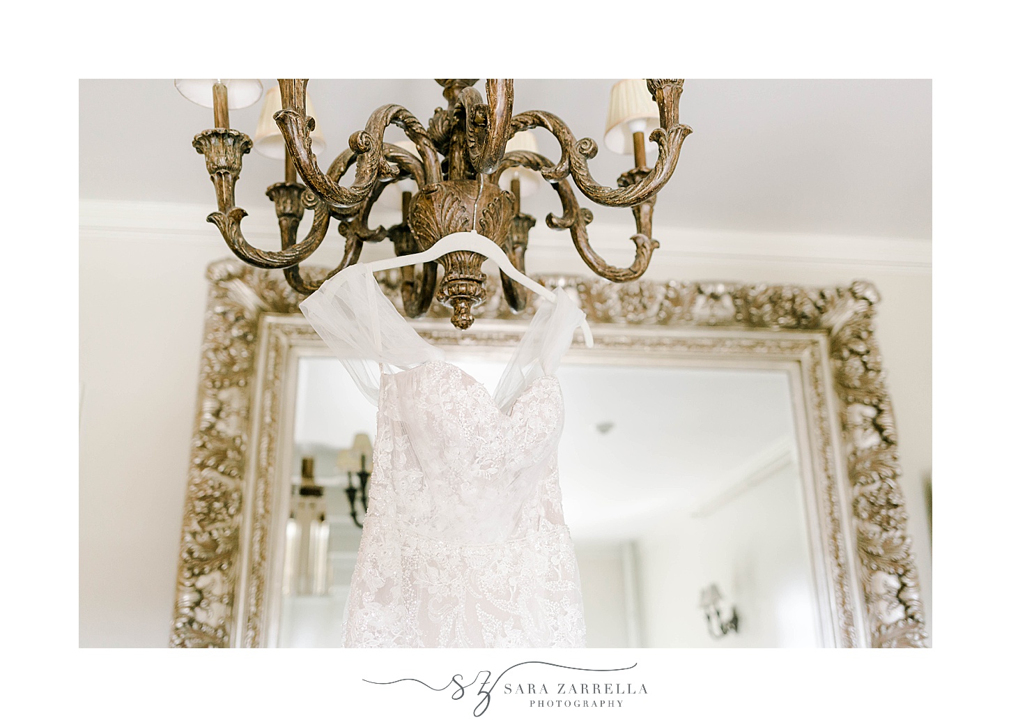 bride's wedding dress hangs on custom hanger from chandelier at OceanCliff Hotel