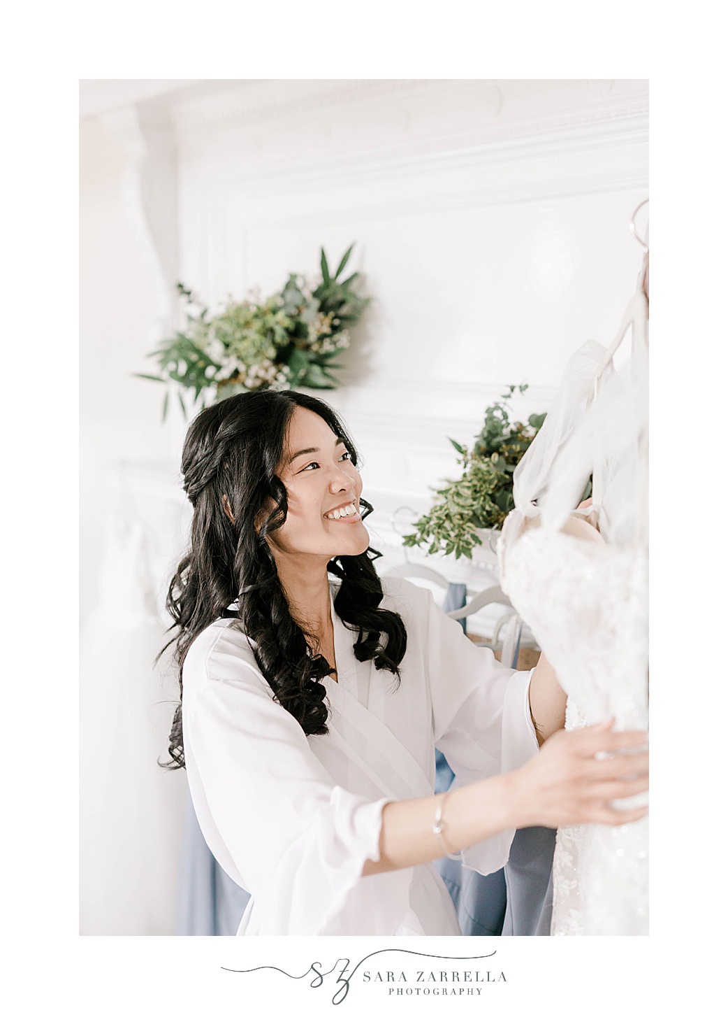 bride smiles at wedding dress hanging inside suite at OceanCliff Hotel
