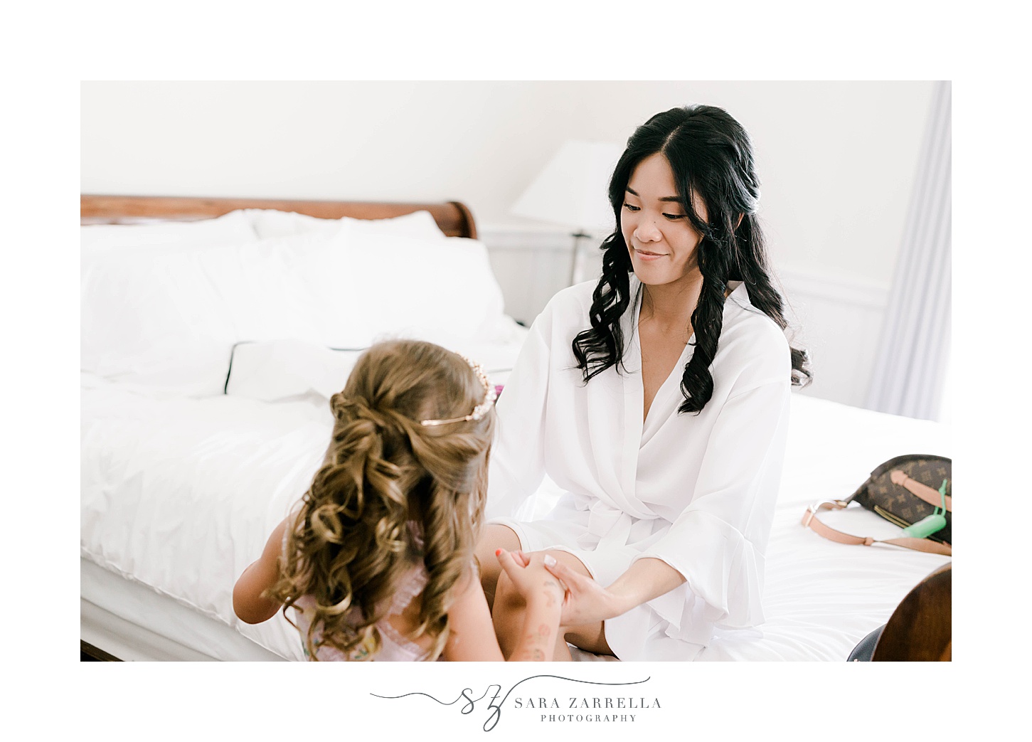 bride smiles at flower girl during prep at OceanCliff Hotel