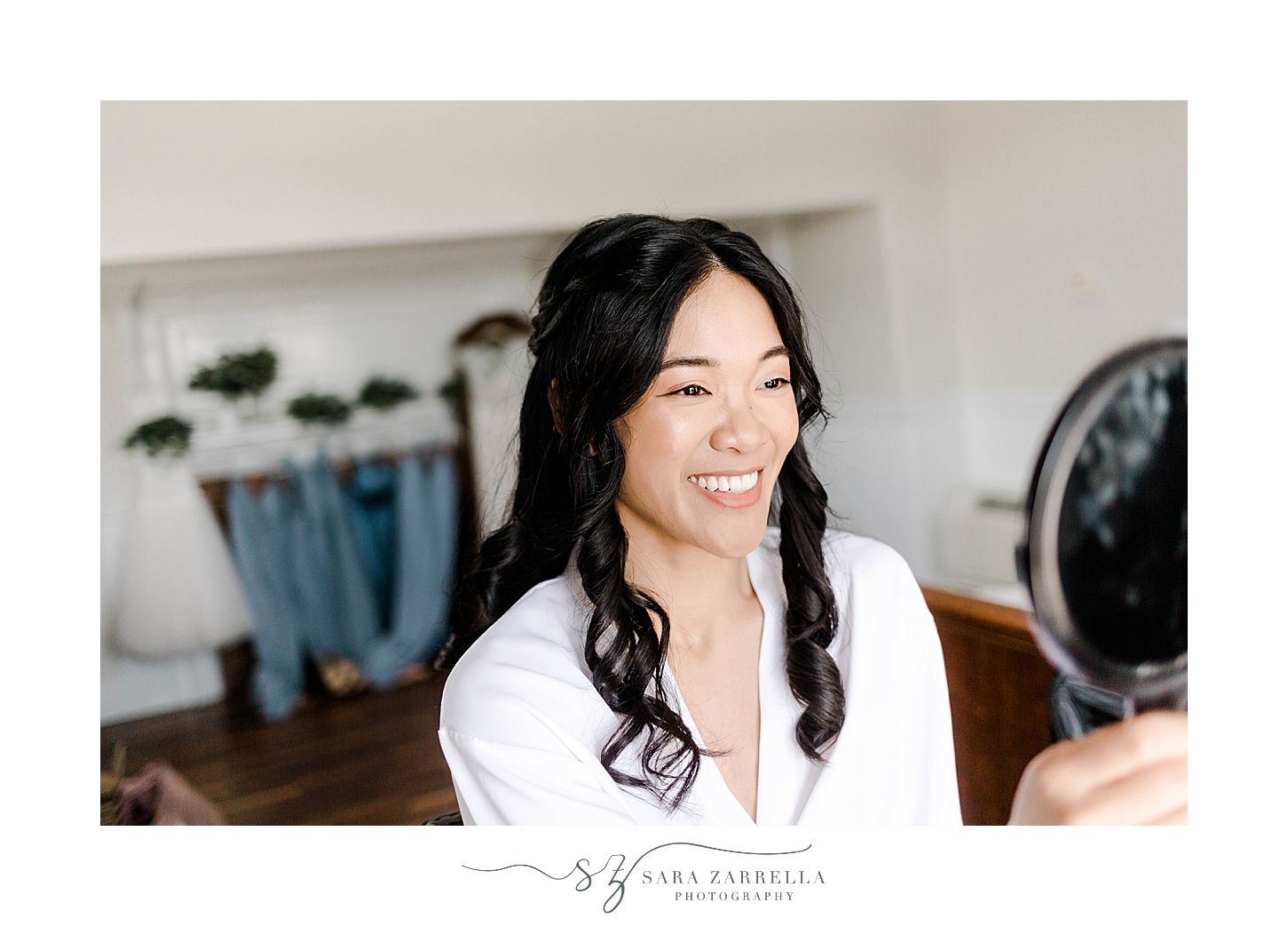 bride smiles in mirror with hair and makeup done 