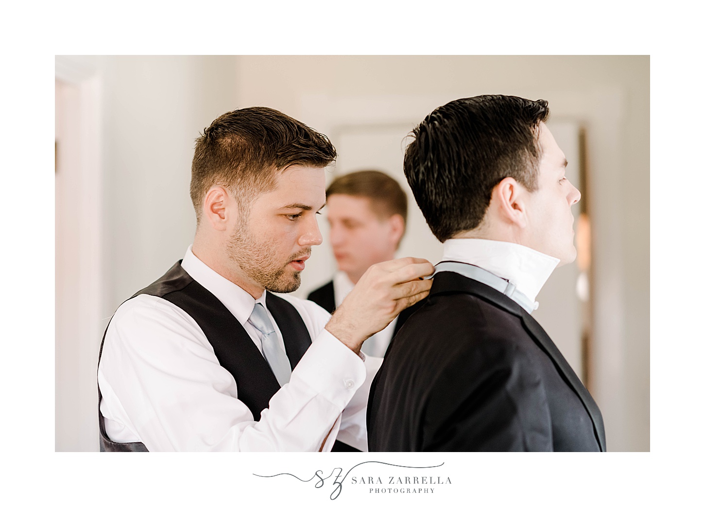groomsman helps groom with bowtie at OceanCliff Hotel
