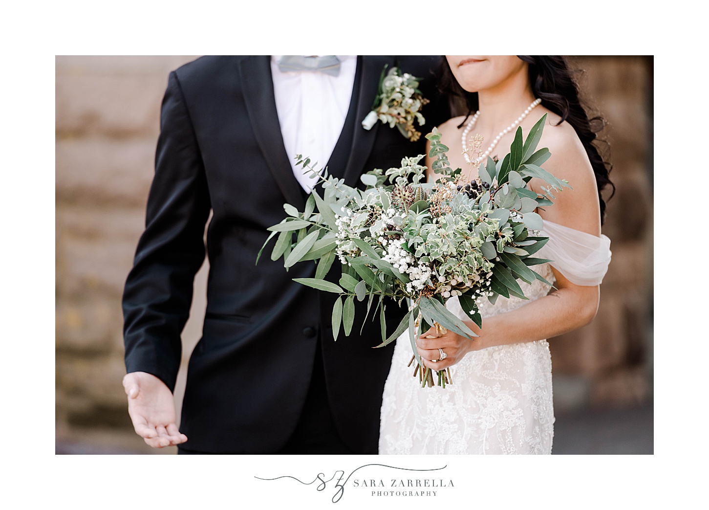 groom hugs bride to him while she holds bouquet of greenery and succulents 