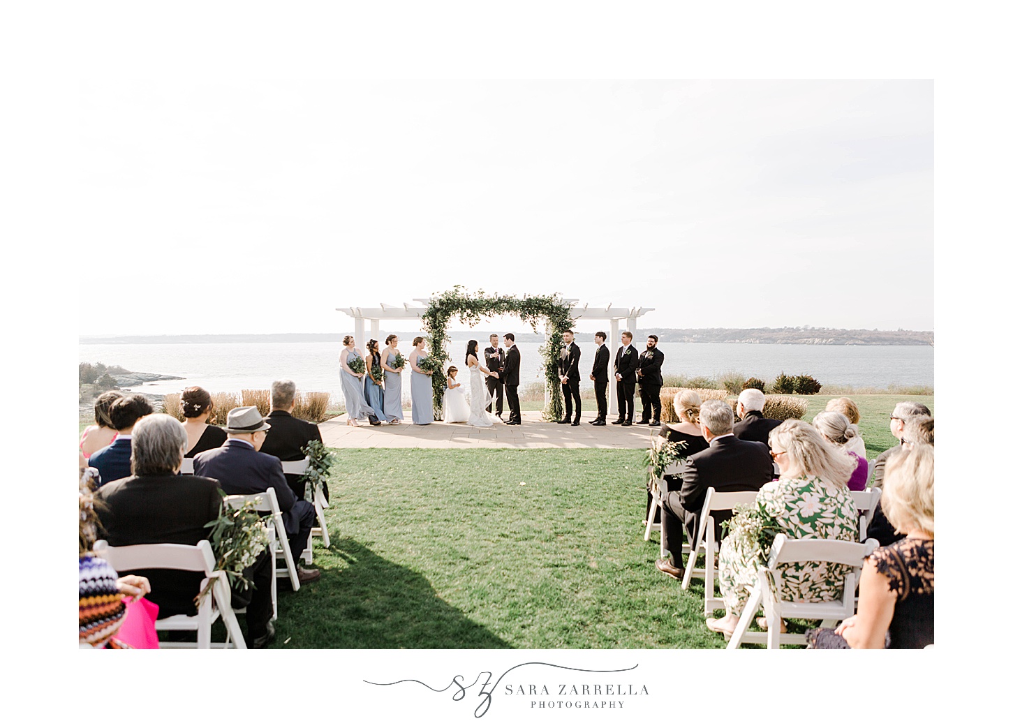 bride and groom stand under arbor for outdoor waterfront wedding ceremony in Newport, RI
